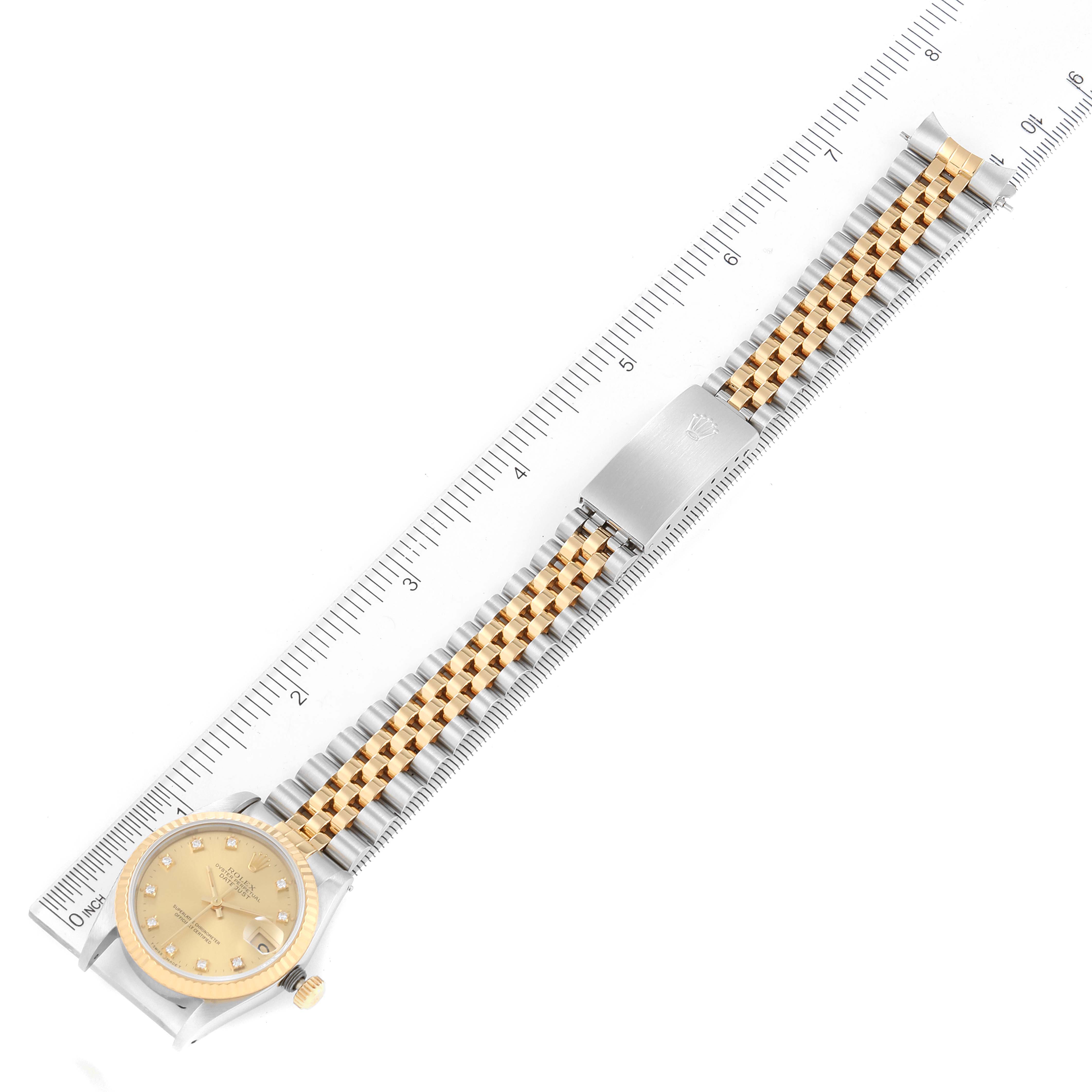 The image shows a top-down view of a Rolex Mid-Size 68273 Women
s Steel and Gold (two tone) Champagne Dial 68273 Women
s Steel and Gold (two tone) Champagne Dial model watch, displaying the dial, bracelet, and clasp alongside a ruler for scale.