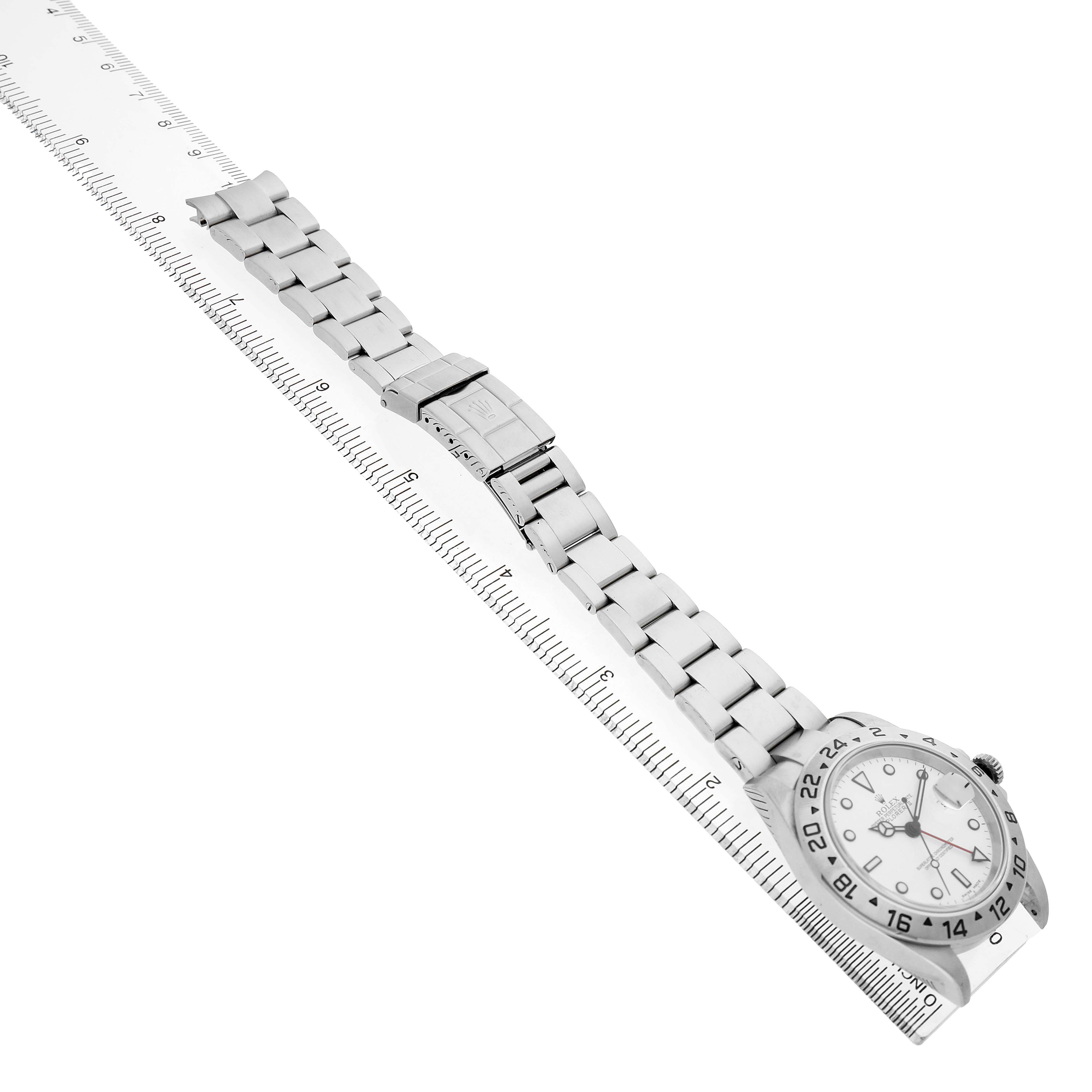 The image shows a Rolex Explorer 16570 T Men's Stainless Steel White Dial watch and band, angled diagonally with the face and bracelet aligned alongside a ruler.