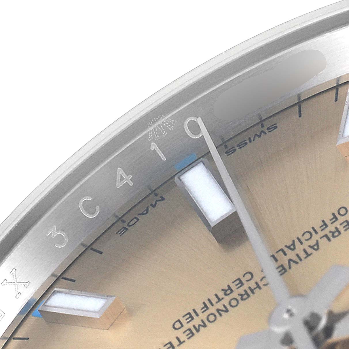 This close-up image shows part of the dial, hour markers, and bezel of a Rolex Oyster Perpetual 114200 Men's Stainless Steel Champagne Dial 114200 Men's Stainless Steel Champagne Dial watch.