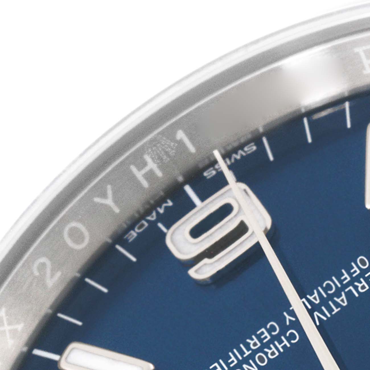 The image shows a close-up view of the dial of a Rolex Oyster Perpetual 116000 Men's Stainless Steel Blue Dial 116000 Men's Stainless Steel Blue Dial watch, featuring the hour markers and part of the hands.