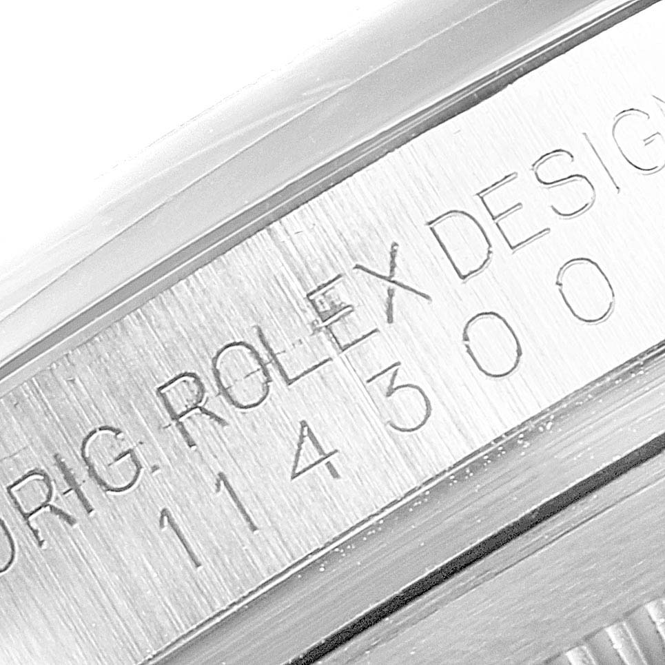 This close-up image focuses on the engraved side of the case of a Rolex Oyster Perpetual 114300 Men's Stainless Steel Blue Dial 114300 Men's Stainless Steel Blue Dial model watch.