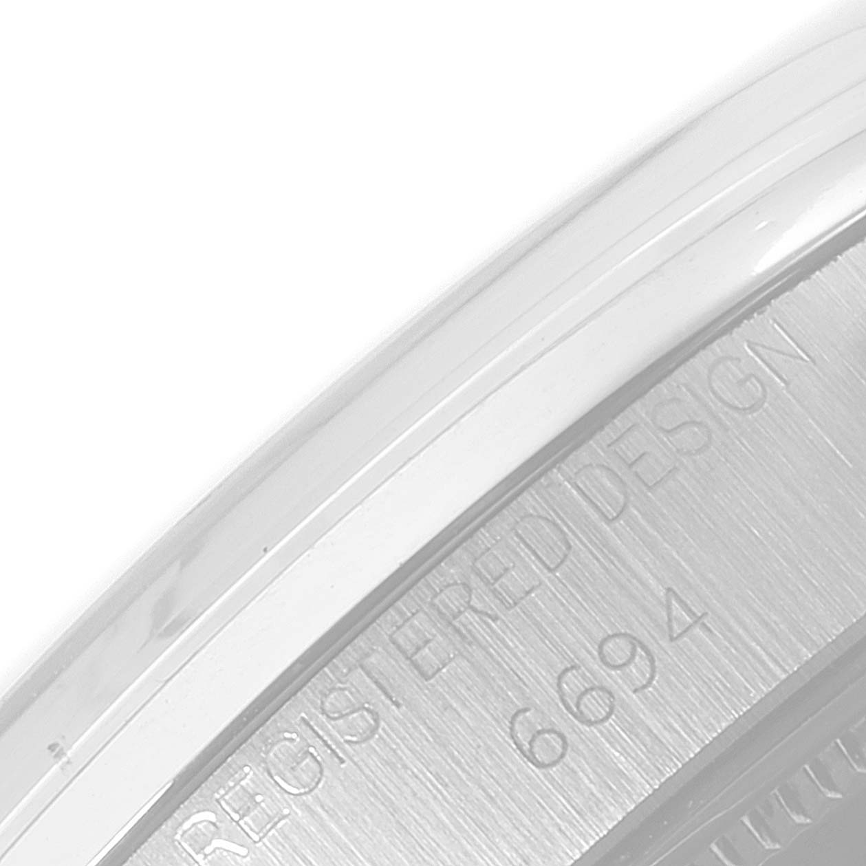 The image shows a close-up of the case back edge of a Rolex Date 6694 Men's Stainless Steel Silver Dial 6694 Men's Stainless Steel Silver Dial model, with the words "REGISTERED DESIGN" and the number "6694" engraved.