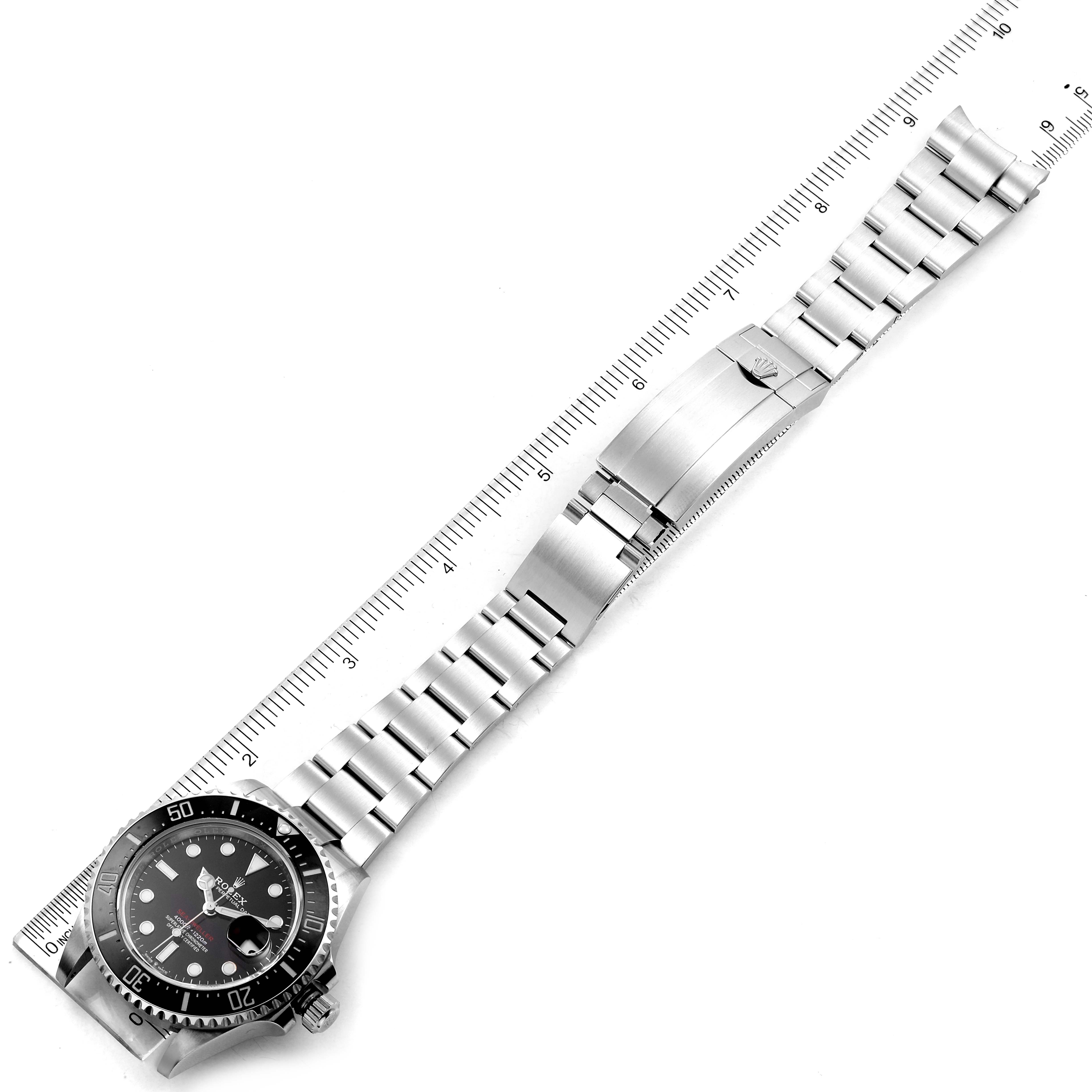 The image shows a full view of a Rolex Sea-Dweller 126600 Men
s Stainless Steel Black Dial 126600 Men
s Stainless Steel Black Dial watch, including its face, bezel, and bracelet, laid next to a ruler for scale.