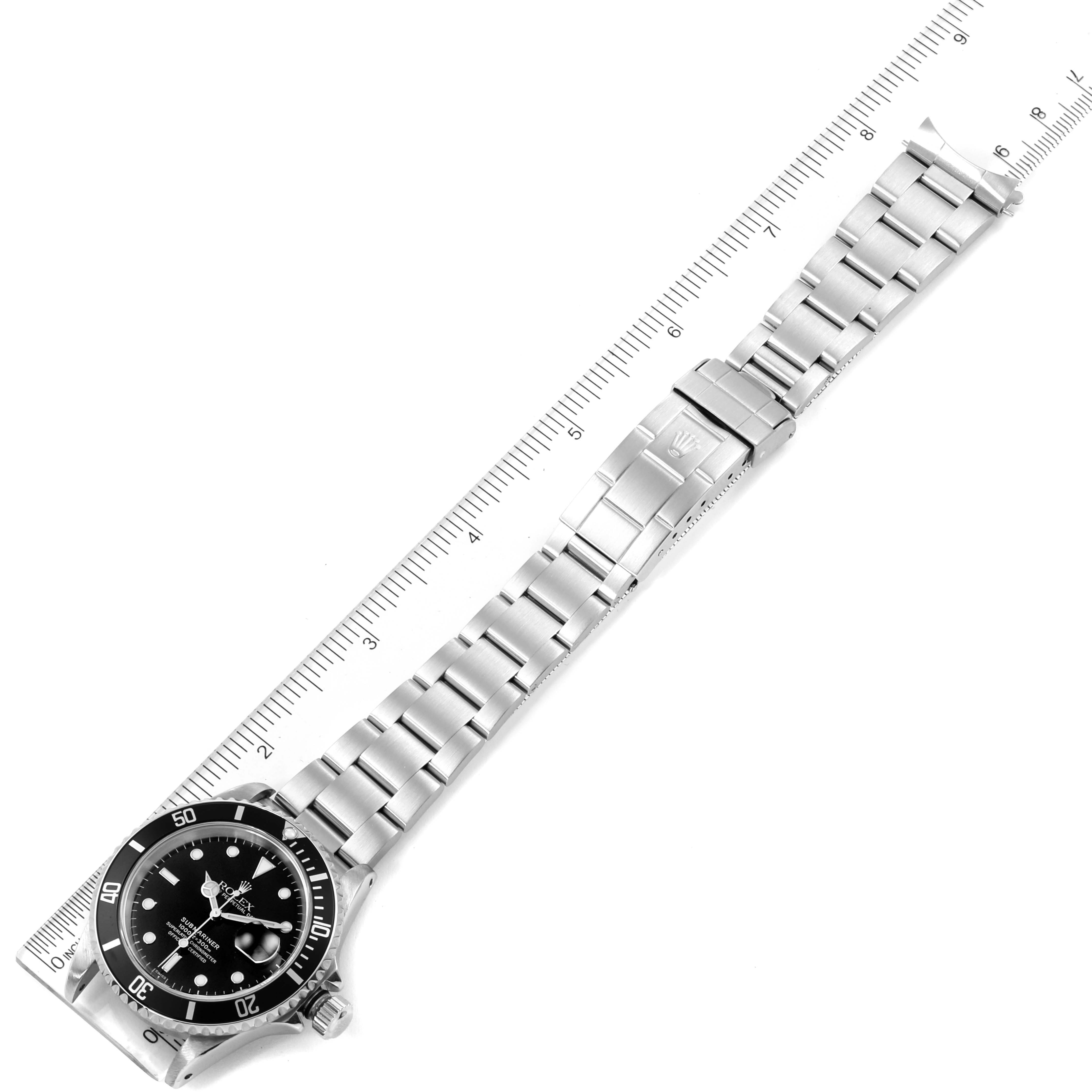 The image shows a Rolex Submariner 16610 Men
s Stainless Steel Black Dial 16610 Men
s Stainless Steel Black Dial watch laid flat with its bracelet fully extended next to a ruler.