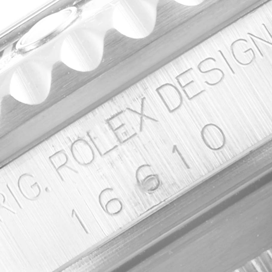 The image shows a close-up of the engraved serial number on the side of the case of a Rolex Submariner 16610 Men
s Stainless Steel Black Dial 16610 Men
s Stainless Steel Black Dial watch, including part of the bezel.
