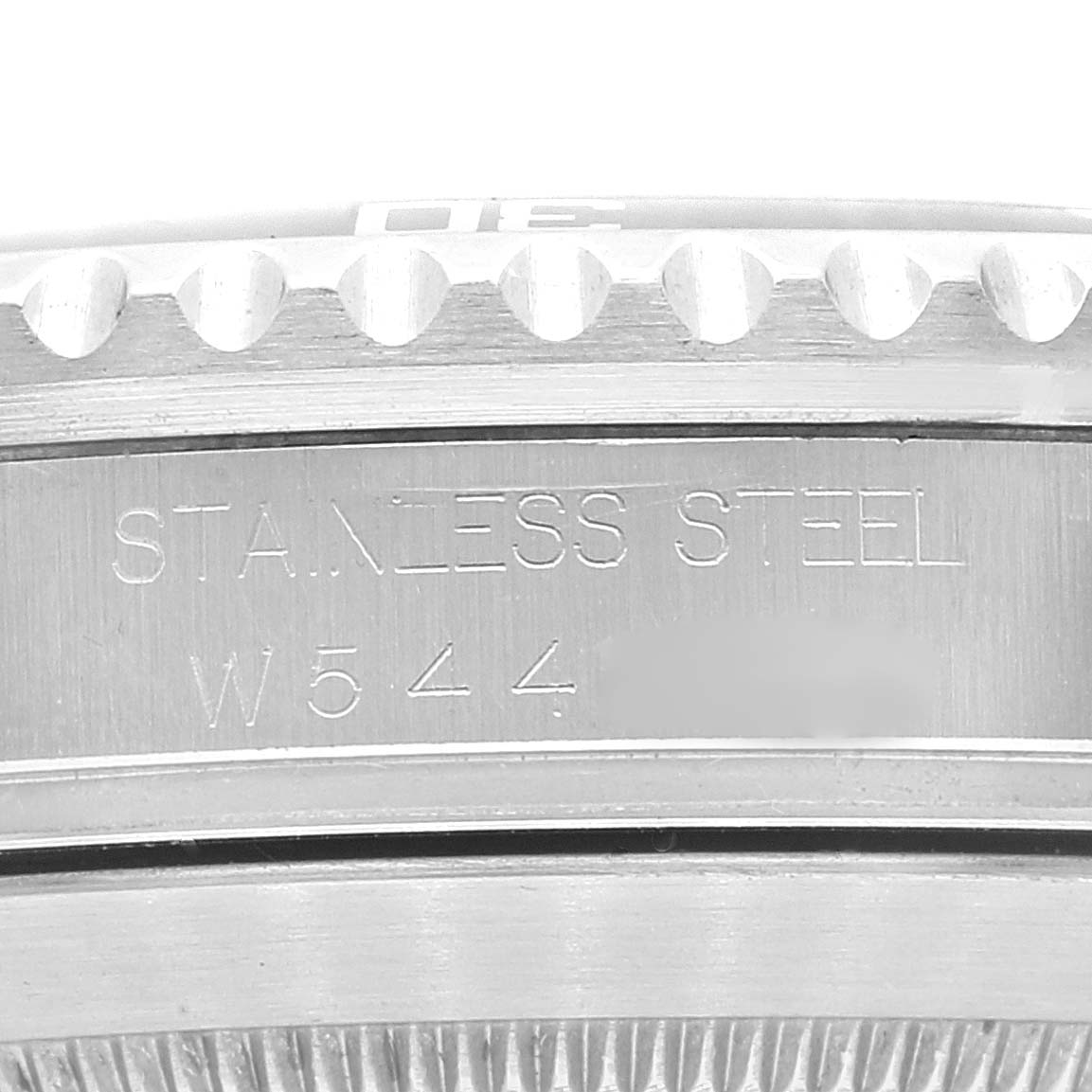 The image shows a close-up of the case side and bezel teeth of a Rolex Submariner 16610 Men
s Stainless Steel Black Dial 16610 Men
s Stainless Steel Black Dial, engraved with "STAINLESS STEEL" and a serial number.
