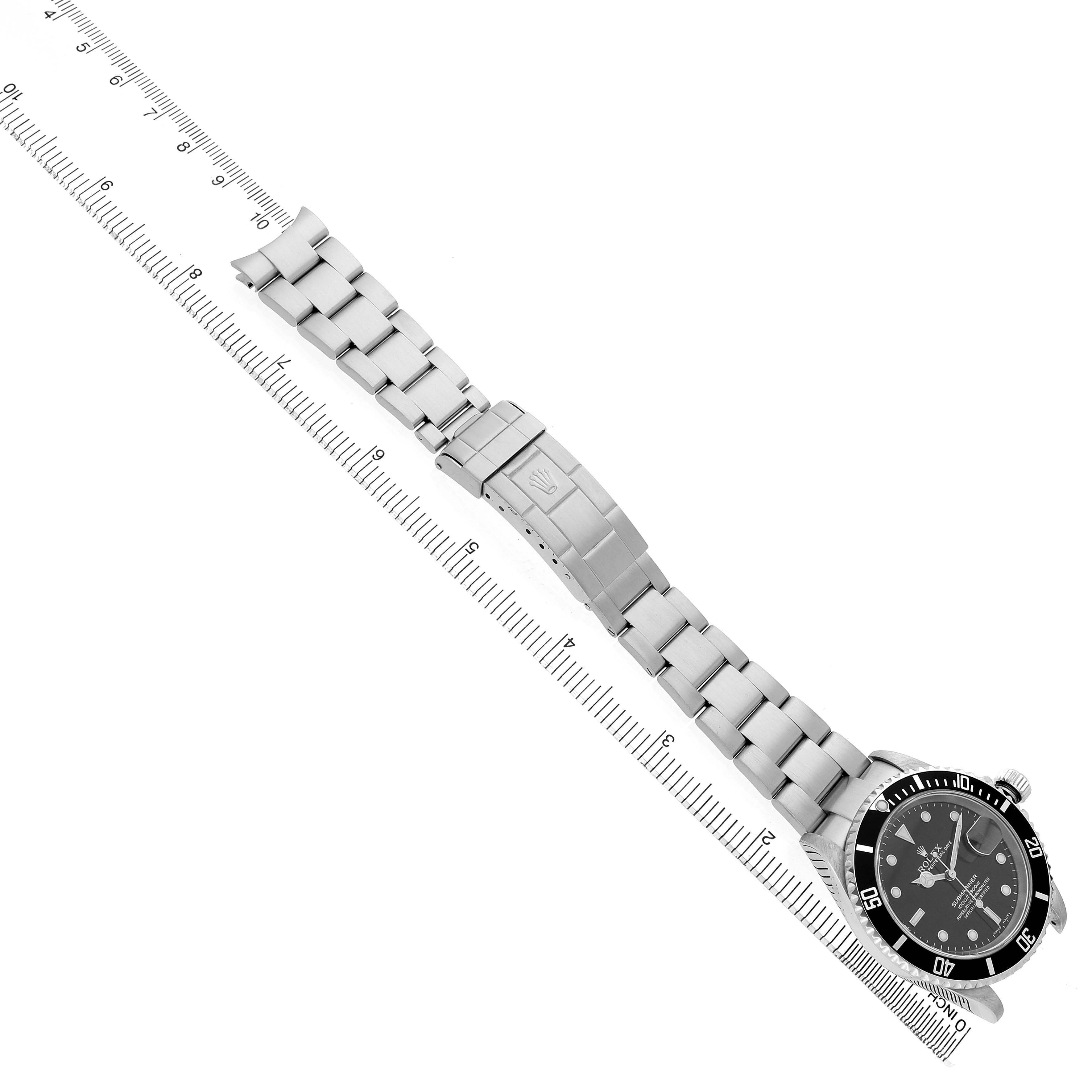 The Rolex Submariner 16610 Men's Stainless Steel Black Dial watch is displayed from a top view, showing the face, bezel, and full bracelet alongside a ruler.