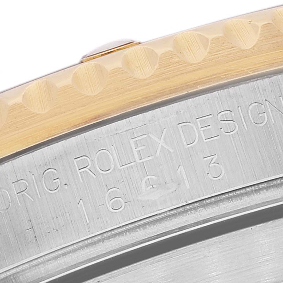 The image shows a macro close-up of the side of the Rolex Submariner 16613 Men's Steel and Gold (two tone) Champagne Dial 16613 Men's Steel and Gold (two tone) Champagne Dial, highlighting the bezel and part of the case with engraved text.