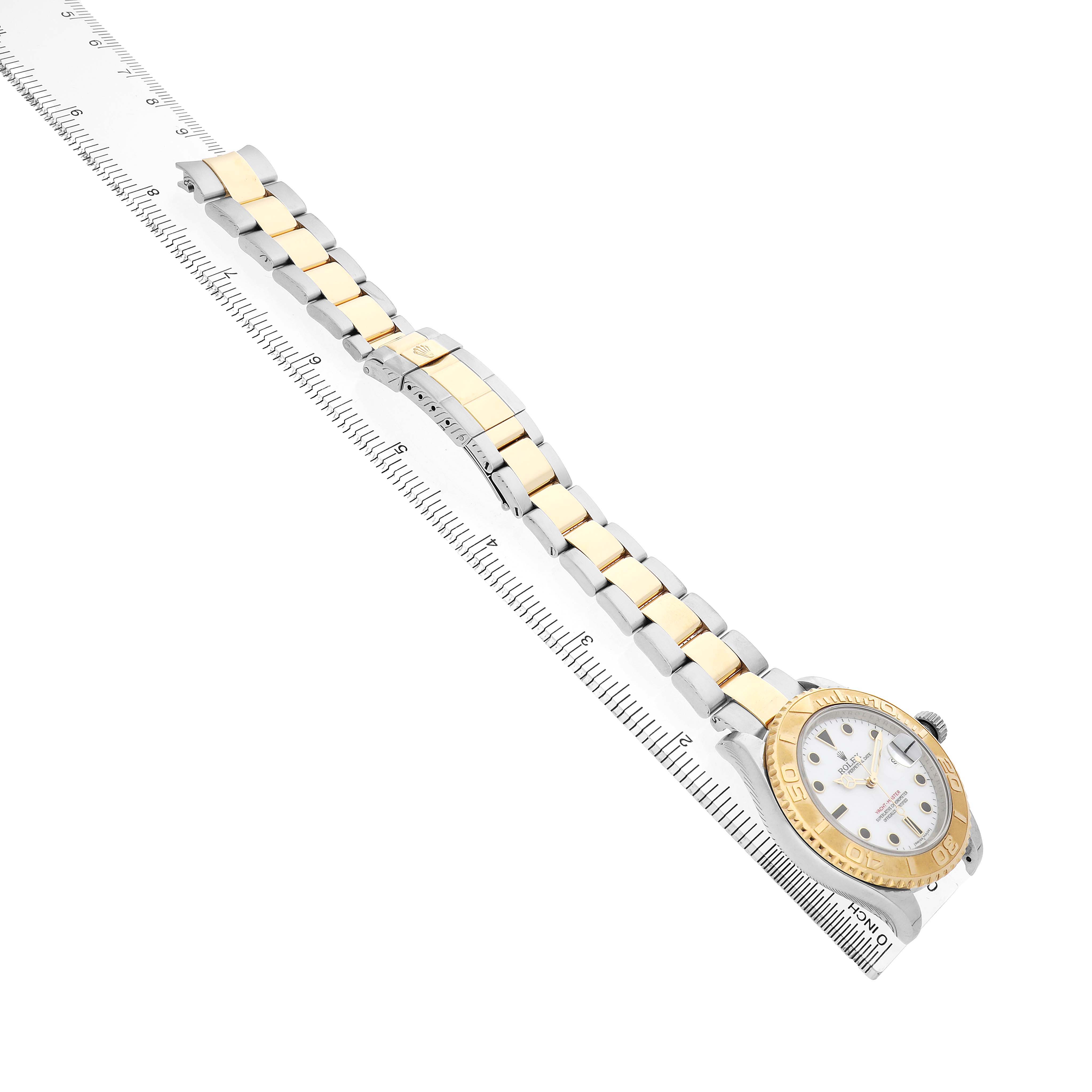 The image shows the Rolex Yacht-Master 16623 Men's Steel and Gold (two tone) White Dial watch from a top view, displaying its dial, bezel, and bracelet alongside a ruler.