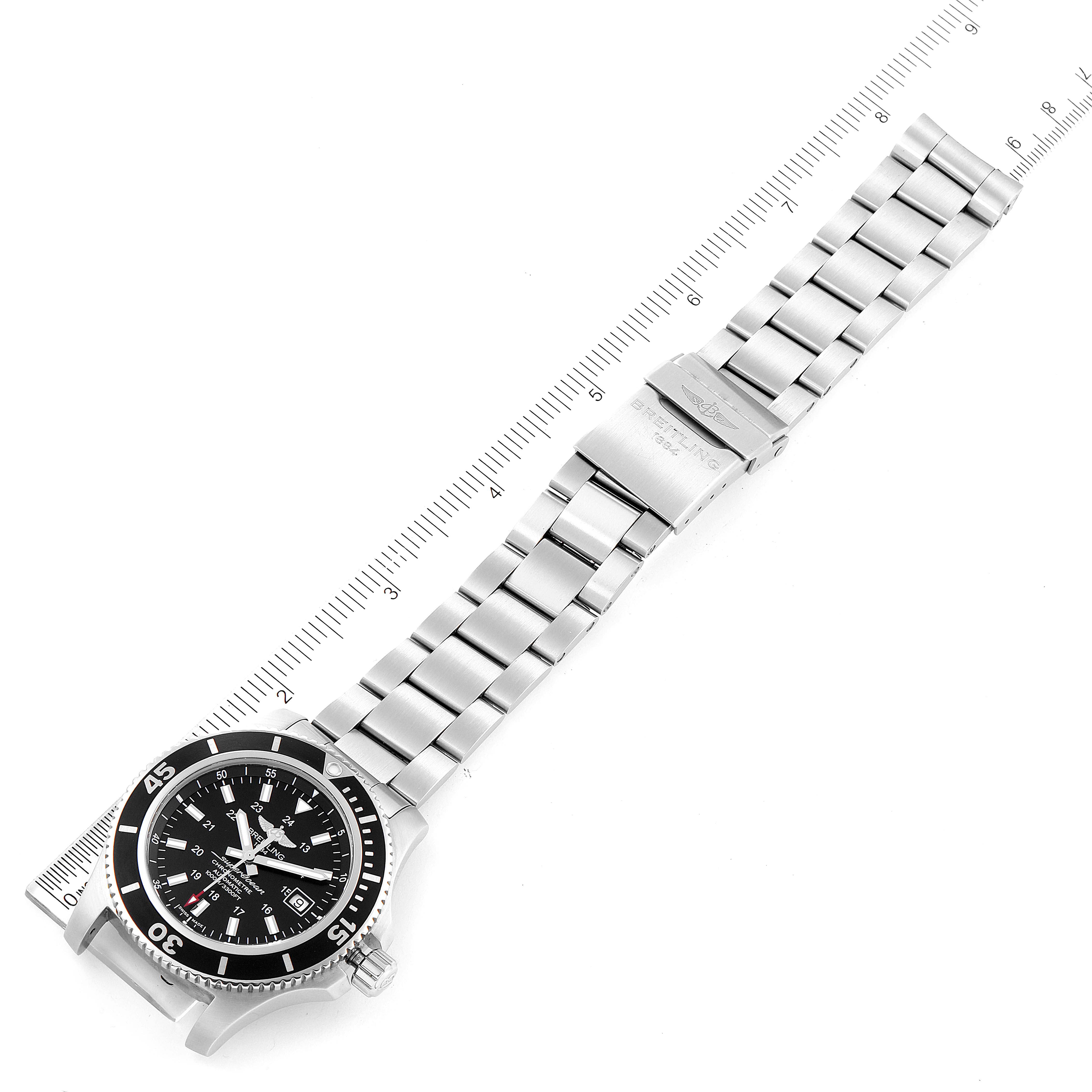 The image shows a top-down view of the Breitling Superocean A17392 Men's Stainless Steel Black Dial A17392 Men's Stainless Steel Black Dial watch with its full metal bracelet and clasp positioned beside a ruler.