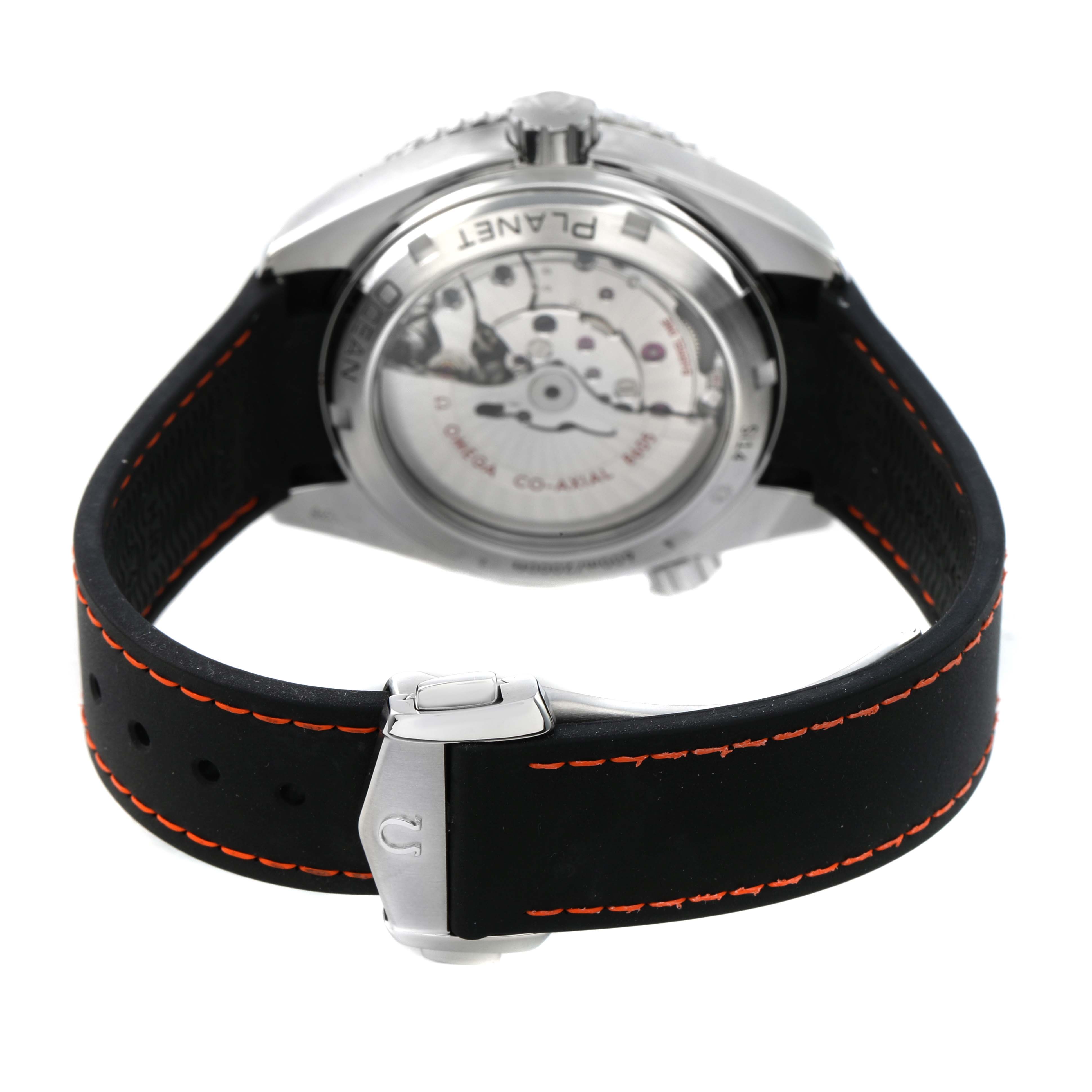 The image shows the back of an Omega Planet Ocean 232.32.44.22.01.002 Men's Stainless Steel Black Dial watch, highlighting the transparent case back and clasp on the strap.