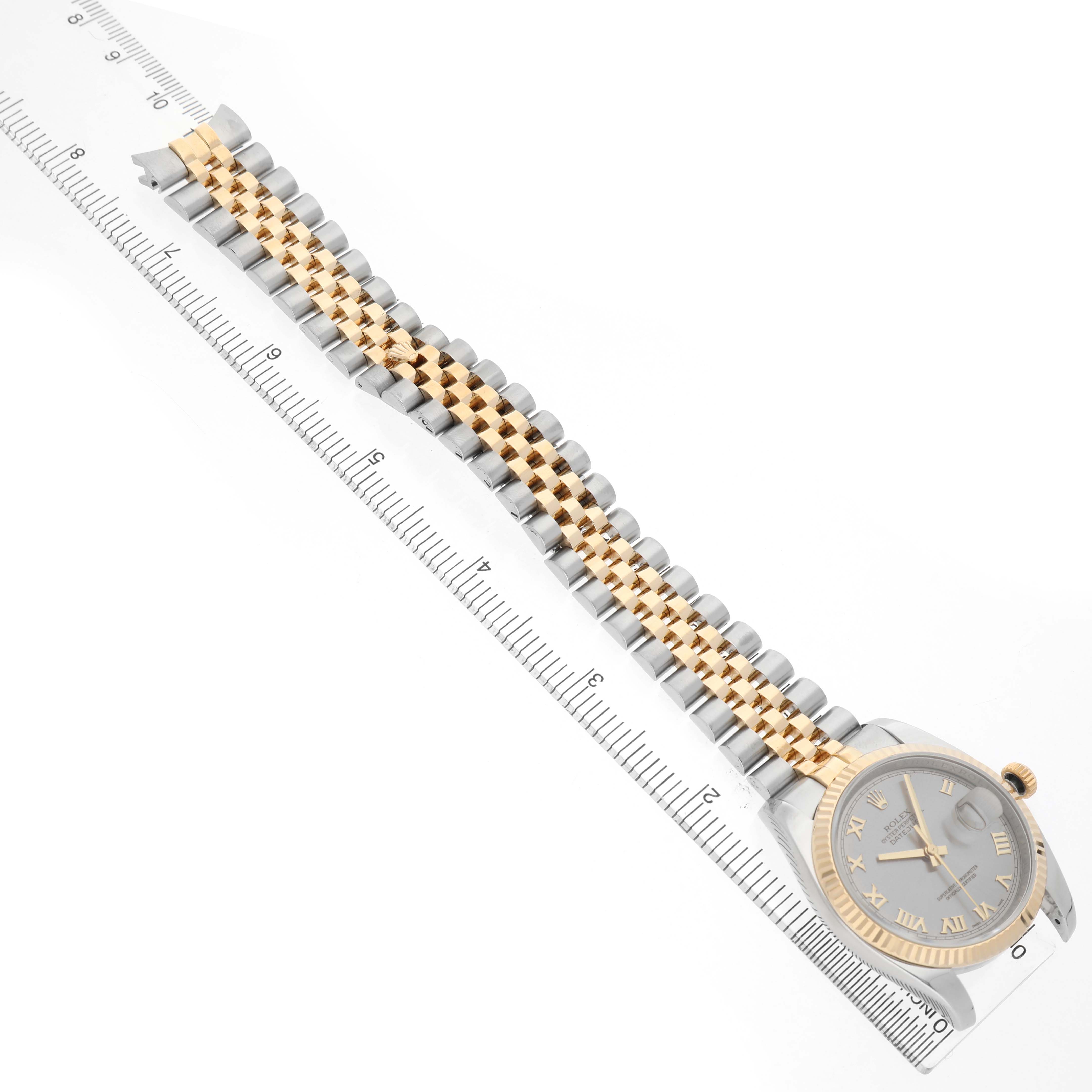 The image shows a Rolex Datejust 116233 Men's Steel and Gold (two tone) Grey Dial watch diagonally positioned, displaying its bracelet alongside a ruler for scale.