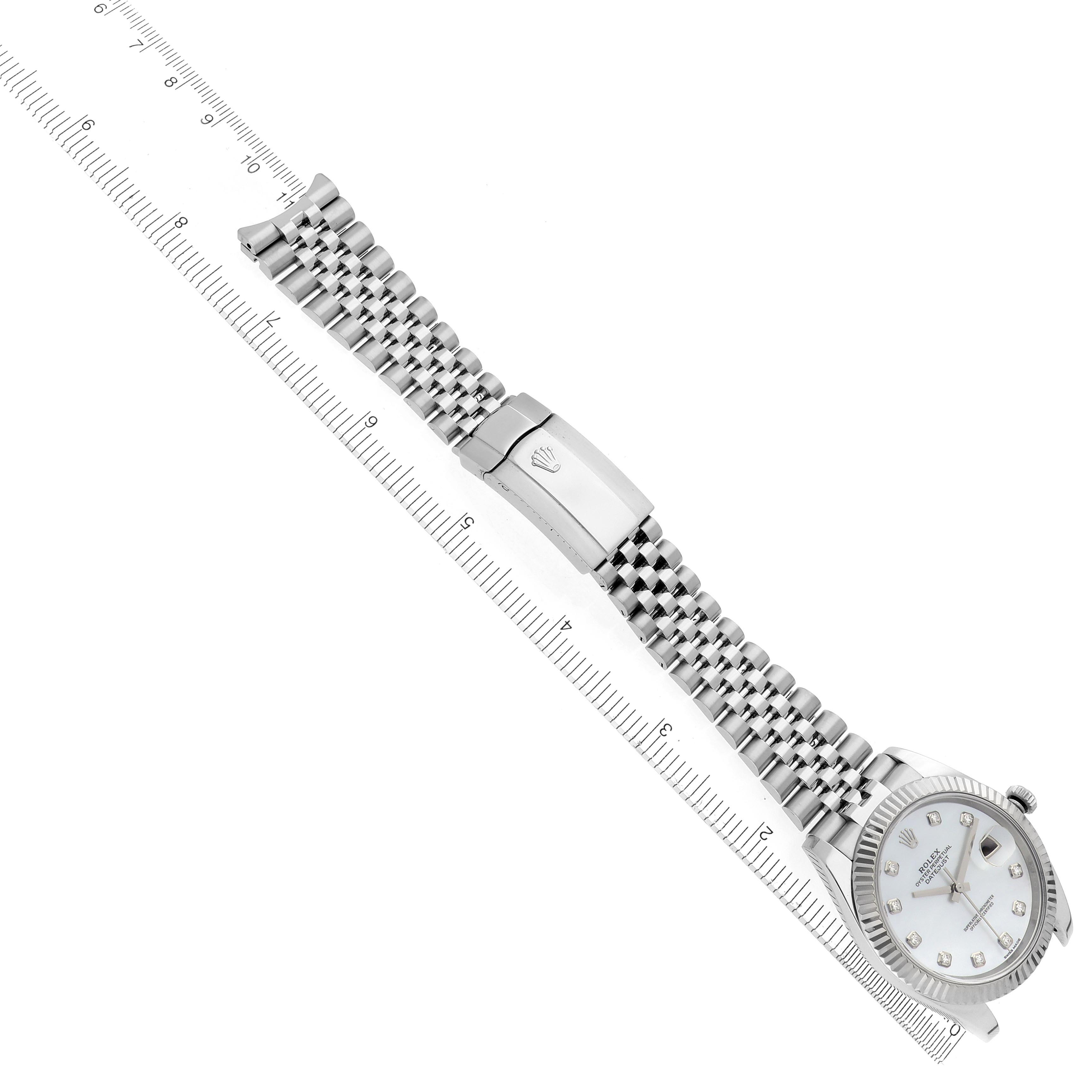 The Rolex Datejust 41 126334 Men's Stainless Steel Mother of Pearl Dial 126334 Men's Stainless Steel Mother of Pearl Dial is shown at an angle displaying the face and Jubilee bracelet with a clasp alongside a ruler for scale.