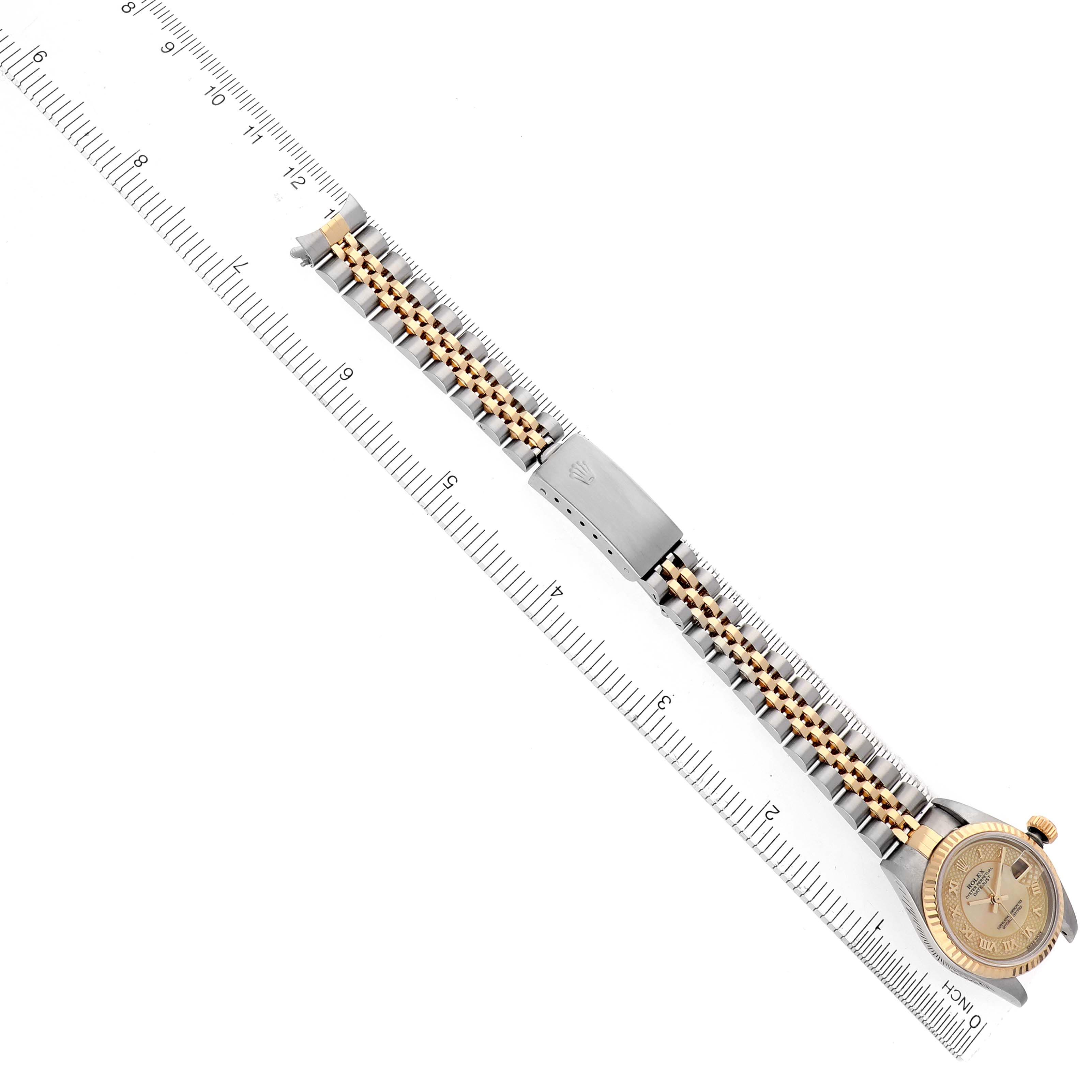The Rolex Datejust 79173 Women's Steel and Gold (two tone) Mother of Pearl Dial 79173 Women's Steel and Gold (two tone) Mother of Pearl Dial watch is shown from a top-down angle, displaying the full bracelet and watch face alongside a ruler for scale.