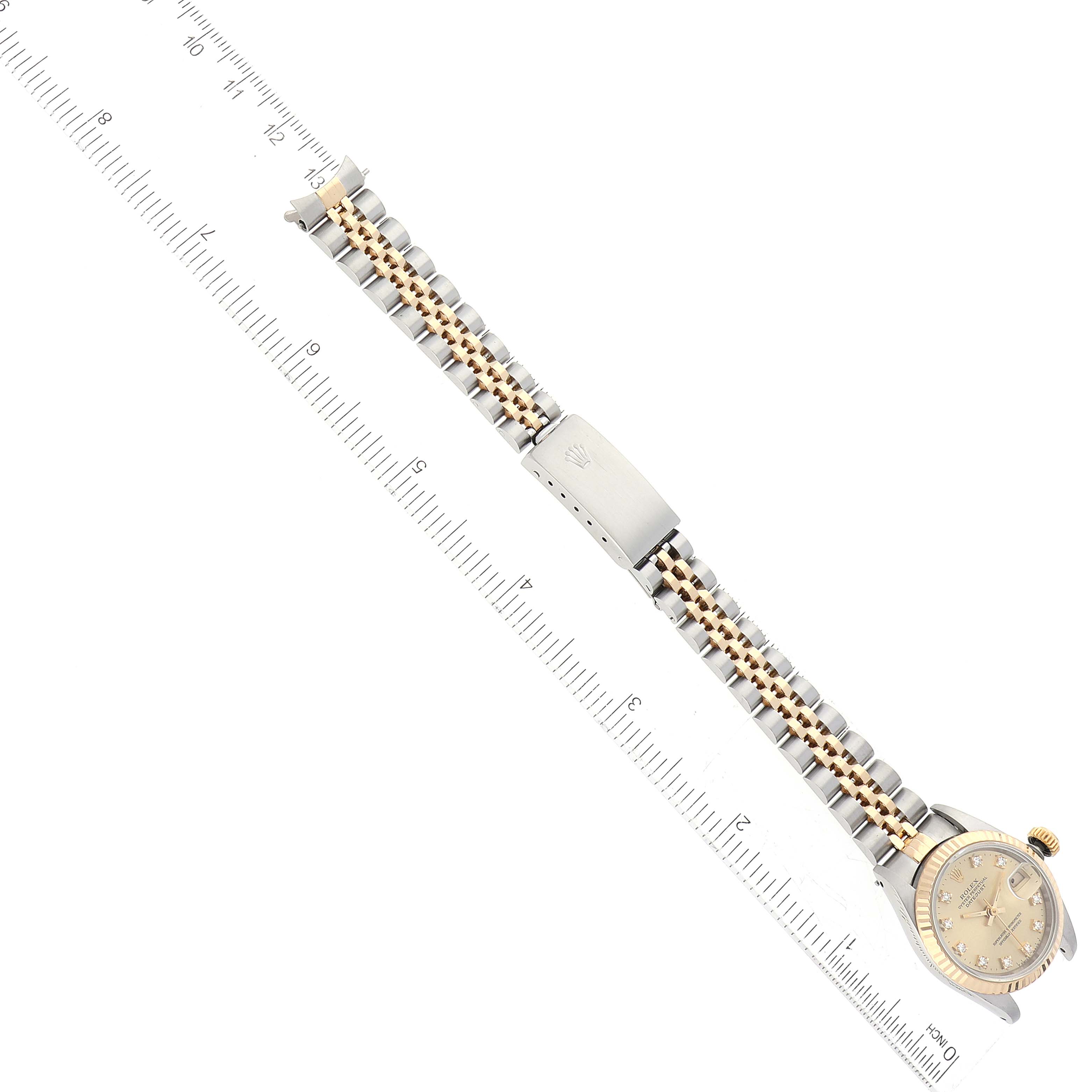 An angled view of a Rolex Datejust 69173G Women's Steel and Gold (two tone) Champagne Dial 69173G Women's Steel and Gold (two tone) Champagne Dial watch shows the watch face, bracelet, and clasp alongside a measuring ruler.