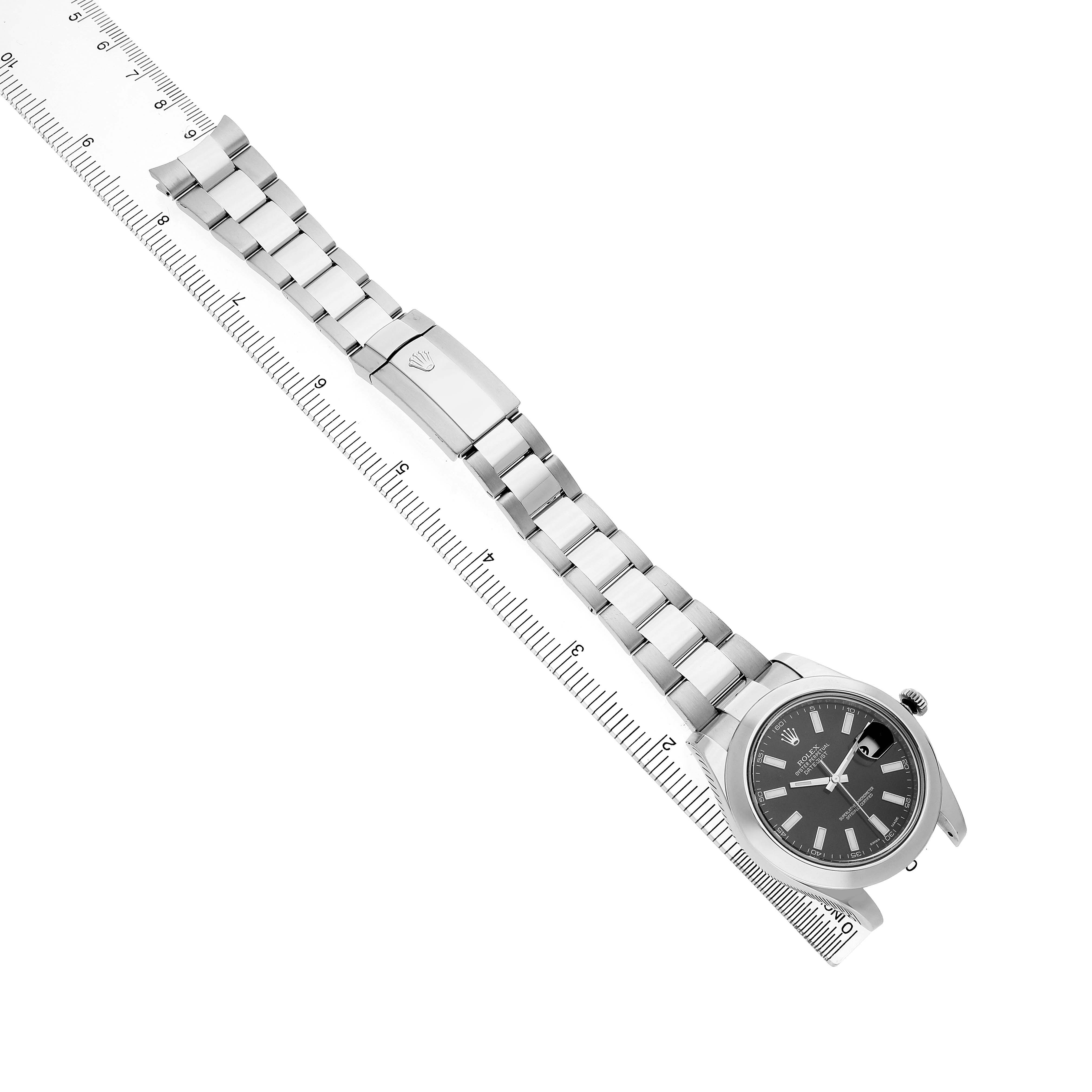 The Rolex Datejust 41 116300 Men's Stainless Steel Black Dial watch is shown from an overhead angle, highlighting the bracelet, clasp, and face near a ruler.