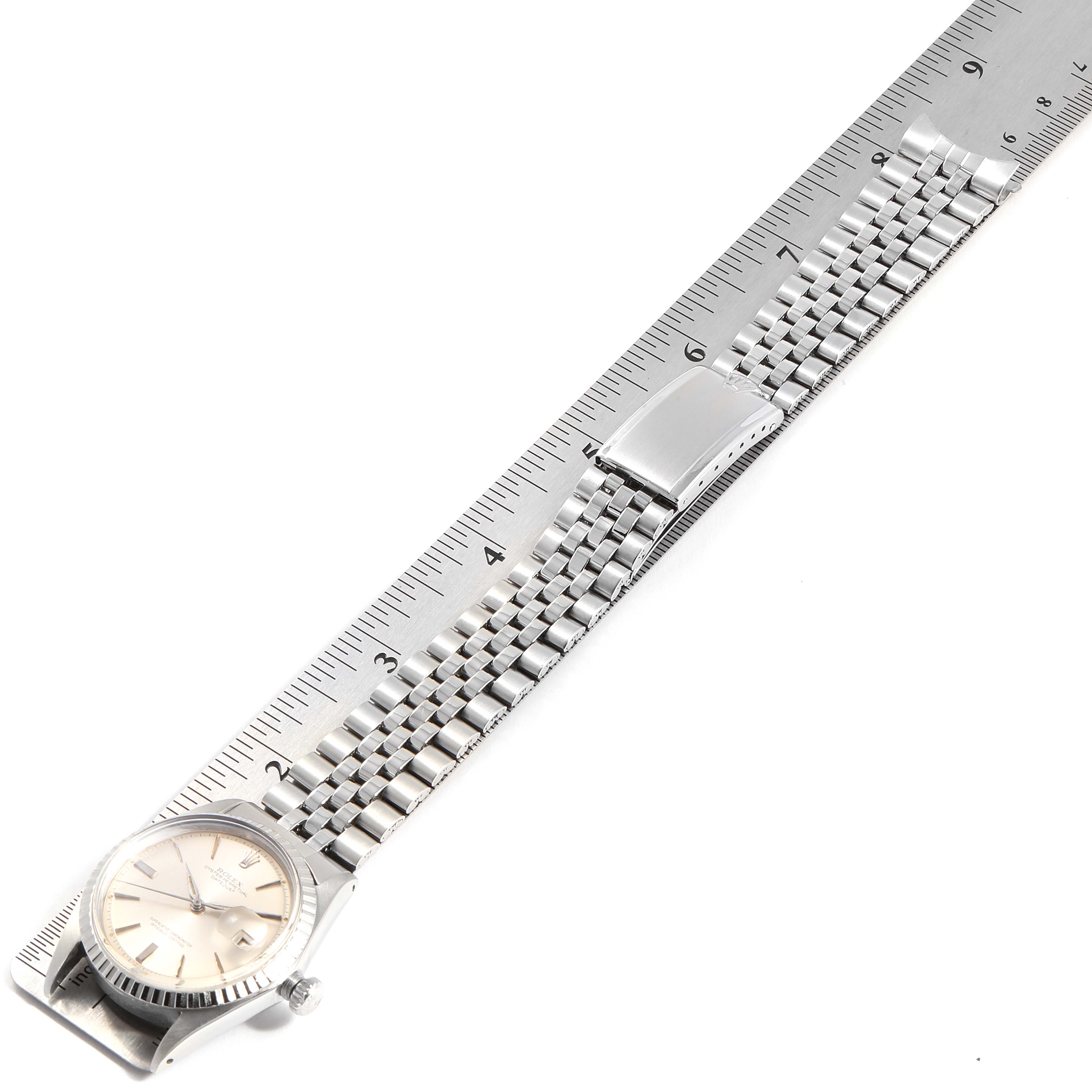 The image shows the Rolex Vintage Collection 1603 Men
s Stainless Steel Silver Dial 1603 Men
s Stainless Steel Silver Dial watch laid flat on a ruler, highlighting the face, bezel, and band.