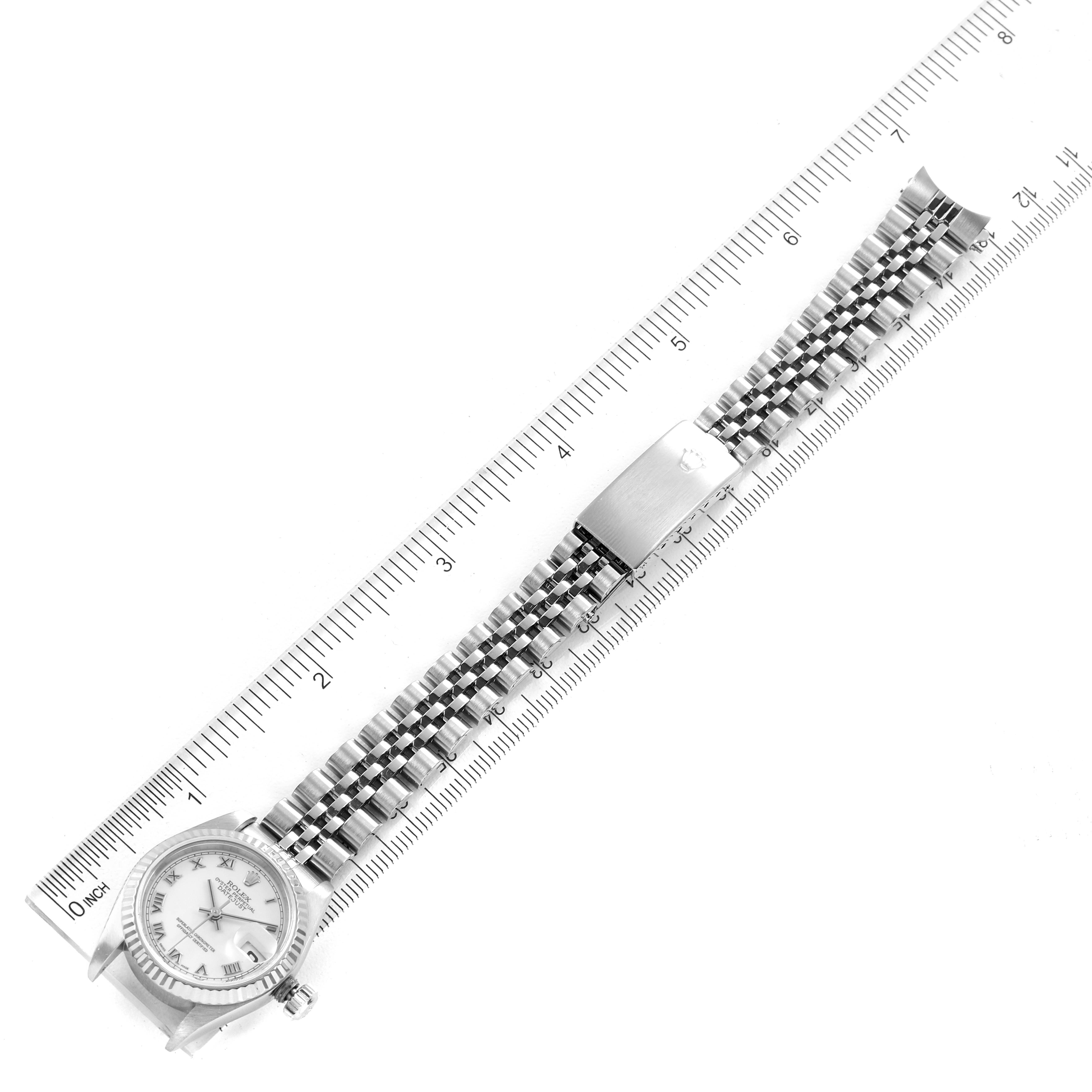 This image shows a top-down view of the Rolex Datejust 79174 Women's Stainless Steel White Dial 79174 Women's Stainless Steel White Dial watch, highlighting the face, band, and clasp next to a ruler.