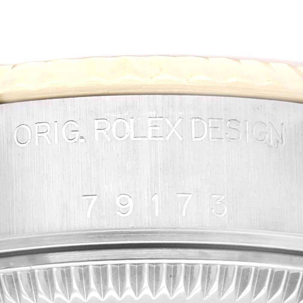 The image shows a close-up of the side of a Rolex Datejust 79173 Women's Steel and Gold (two tone) Champagne Dial 79173 Women's Steel and Gold (two tone) Champagne Dial watch with the bezel and engraved serial number.