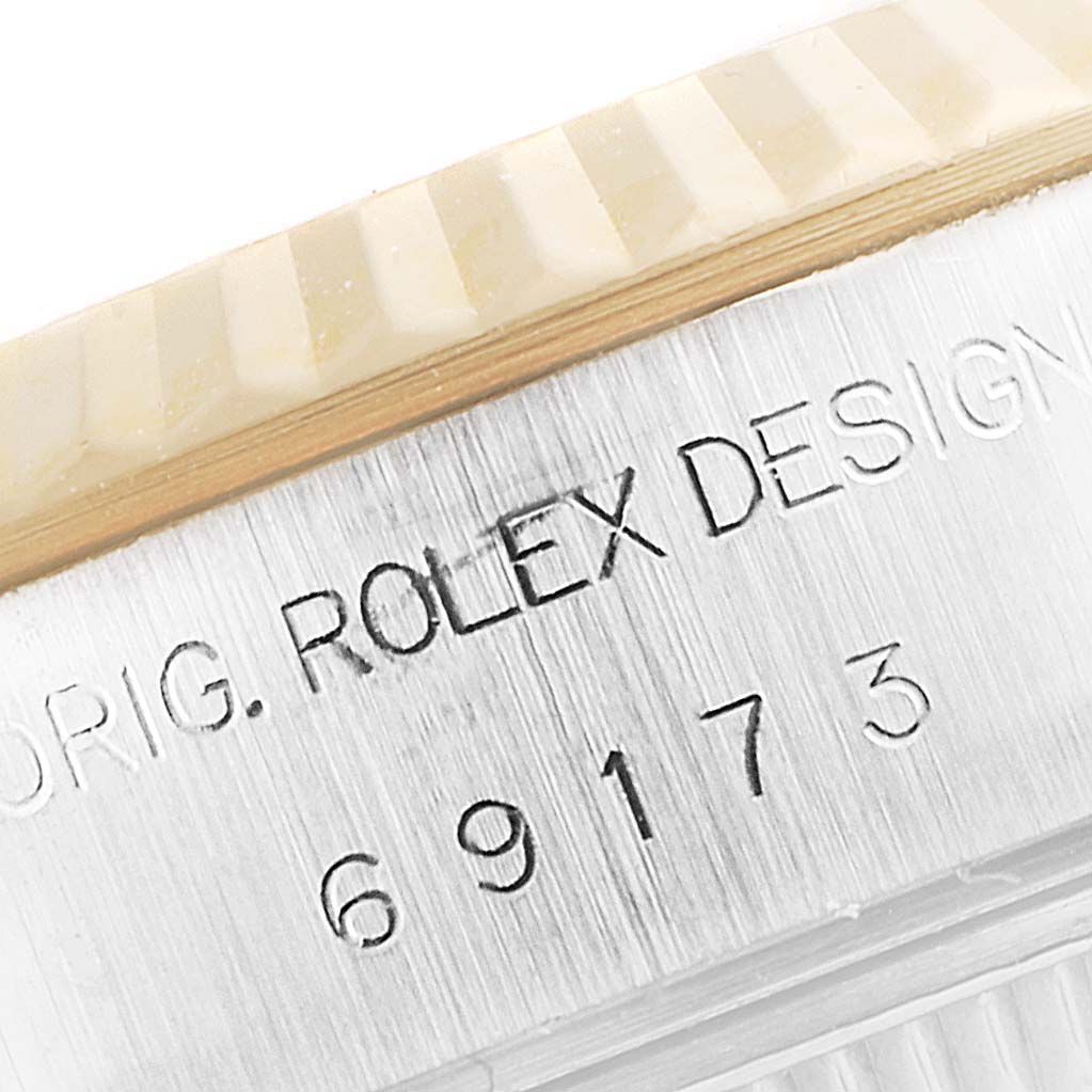 This image shows a close-up of the engraved serial numbers and lettering on the side of the bezel of a Rolex Datejust 69173 Women's Steel and Gold (two tone) Mother of Pearl Dial 69173 Women's Steel and Gold (two tone) Mother of Pearl Dial watch.
