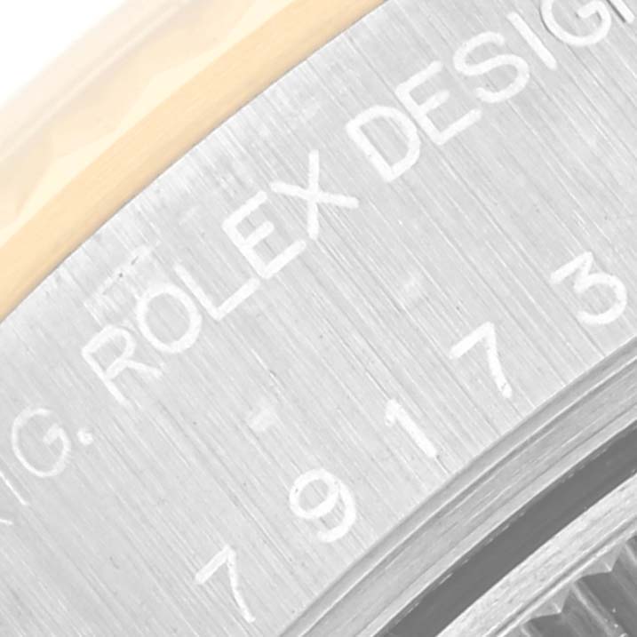 The image shows a close-up of the side of a Rolex Datejust 79173 Women's Steel and Gold (two tone) White Dial 79173 Women's Steel and Gold (two tone) White Dial watch, highlighting part of the bezel and engraved text.