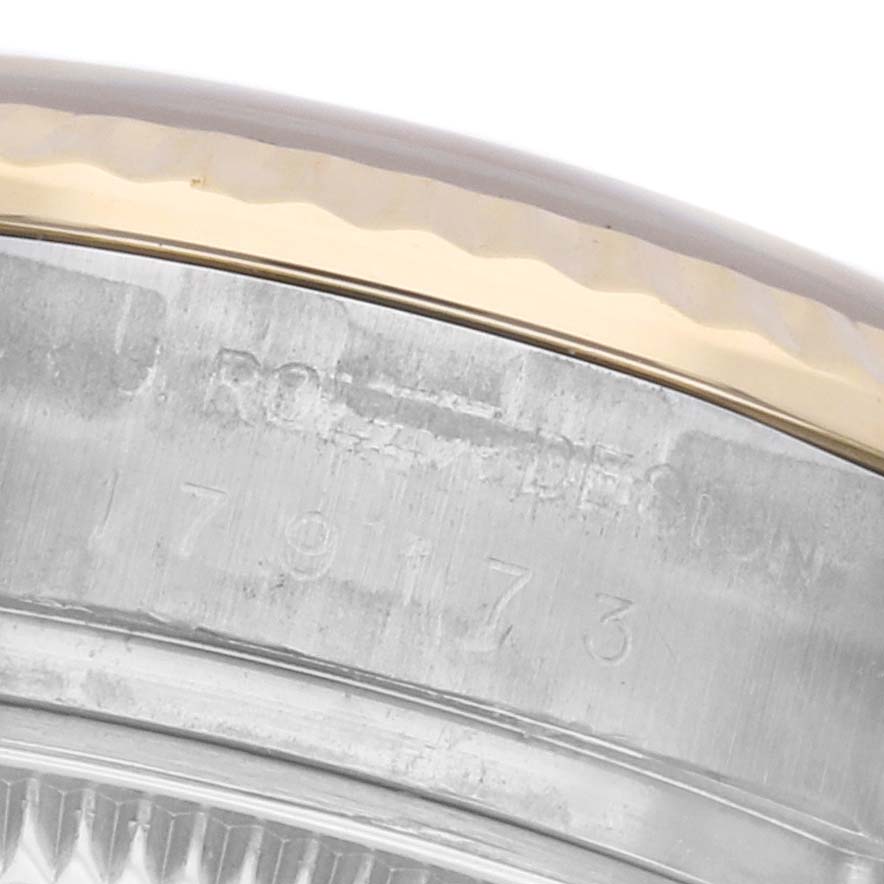 The image shows a close-up angle of the bezel and part of the case of a Rolex Datejust 179173 Women's Steel and Gold (two tone) White Dial 179173 Women's Steel and Gold (two tone) White Dial watch, highlighting the metal and engraved details.