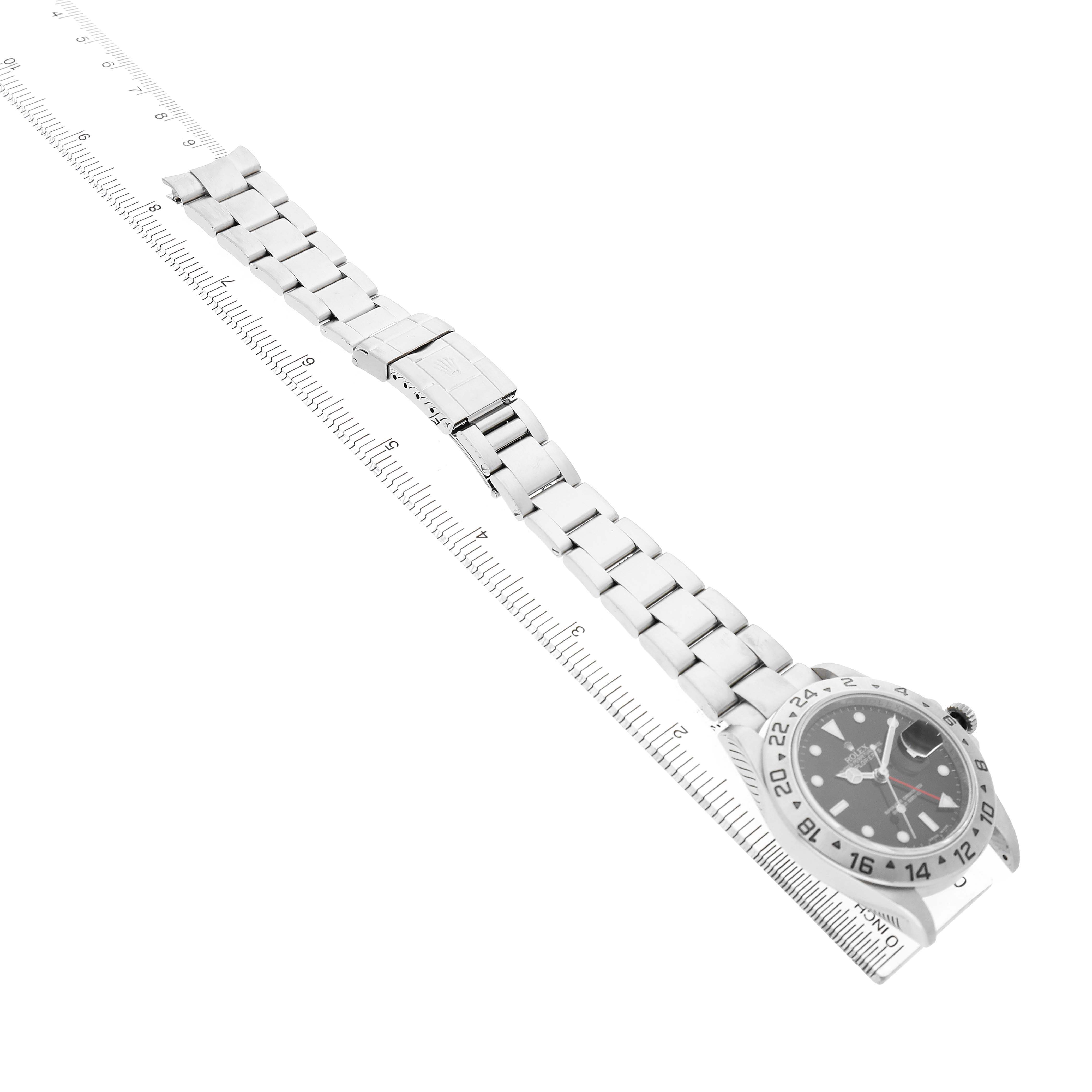 The Rolex Explorer 16570 T Men's Stainless Steel Black Dial watch is shown from a top-down angle with its bracelet extended alongside a ruler for scale.