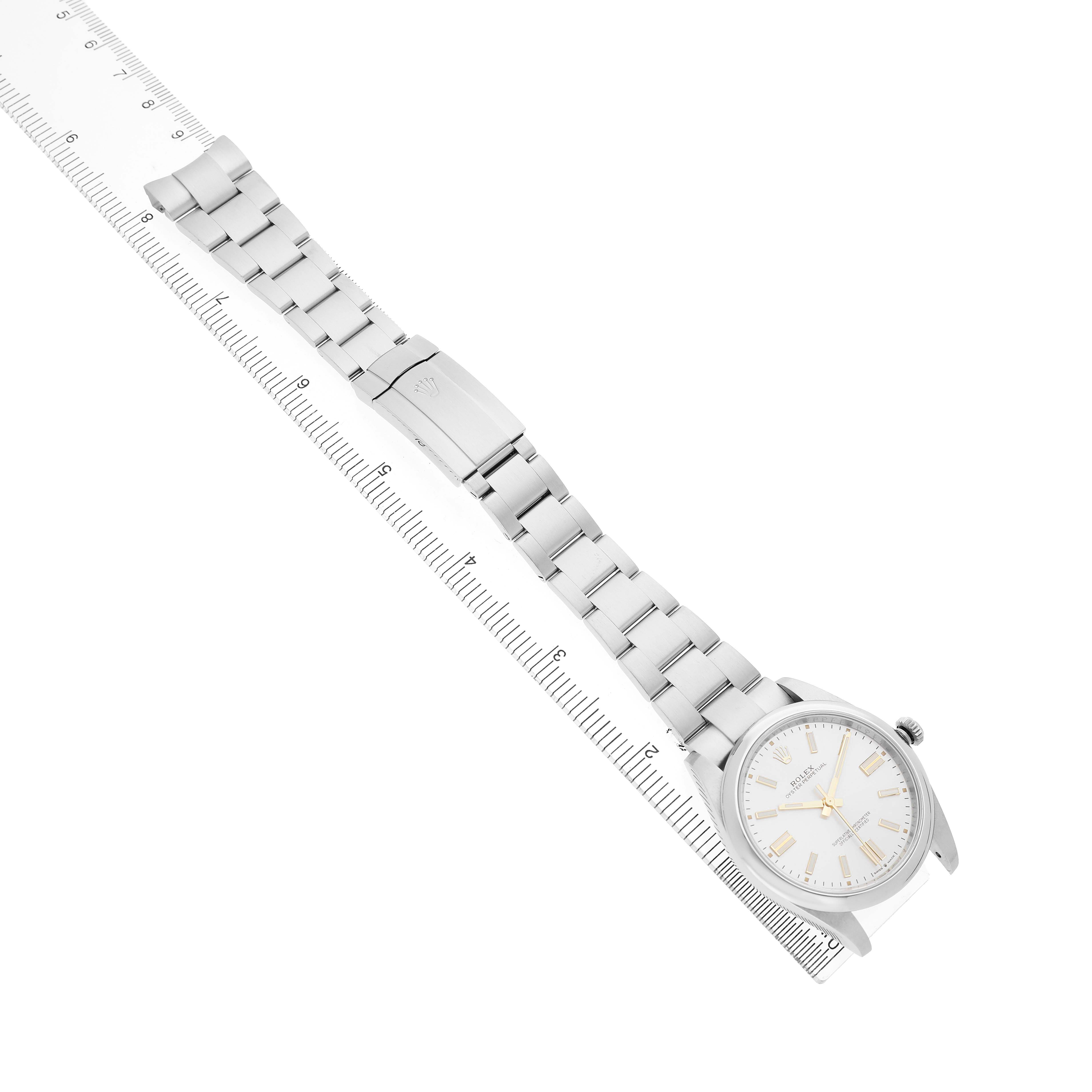 The Rolex Oyster Perpetual 124300 Men's Stainless Steel Silver Dial watch is shown diagonally with a full view of its bracelet and clasp, alongside a ruler for scale.