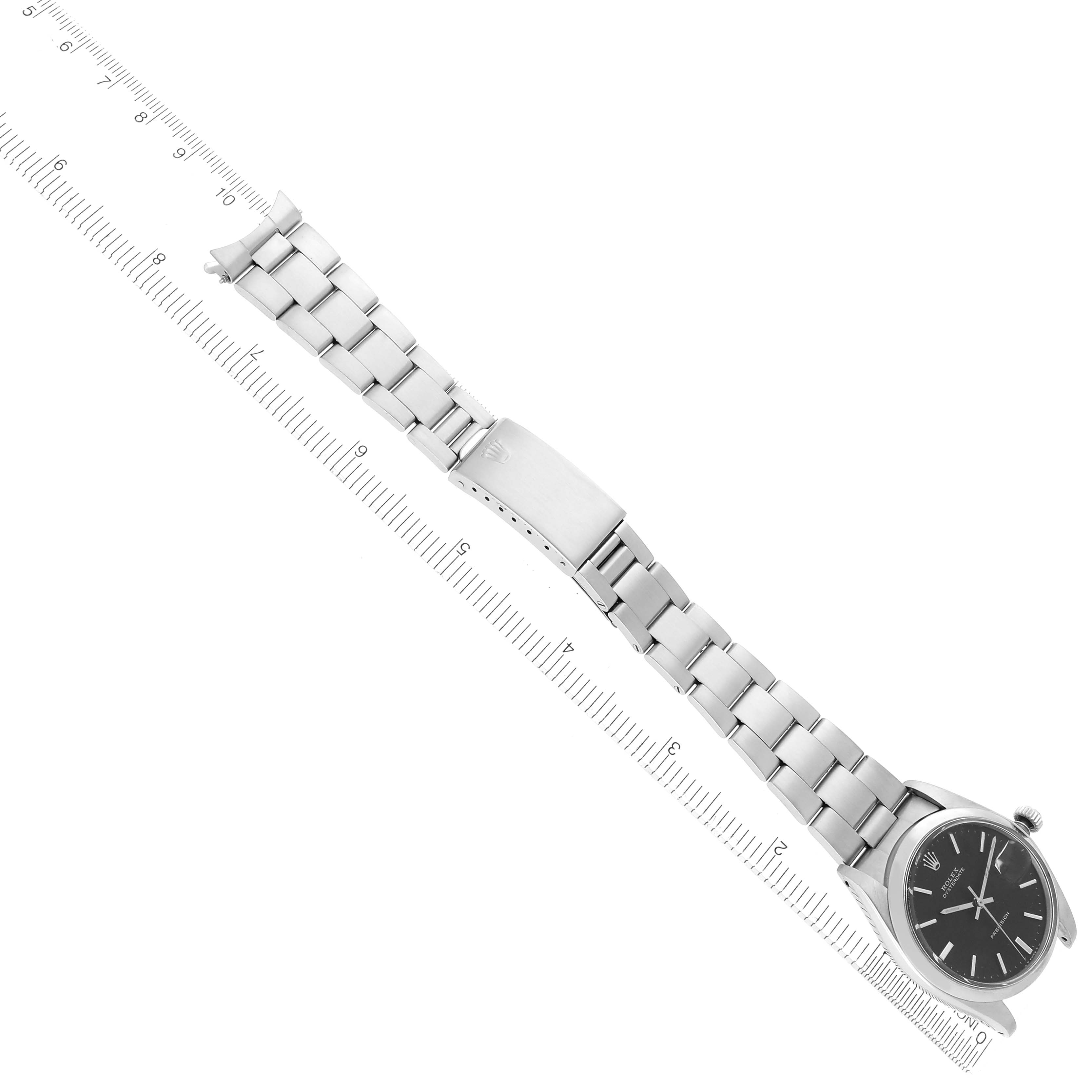 The image shows a Rolex Date 6694 Men's Stainless Steel Black Dial watch from a top-down angle, displaying the dial, bracelet, and clasp aligned with a ruler.