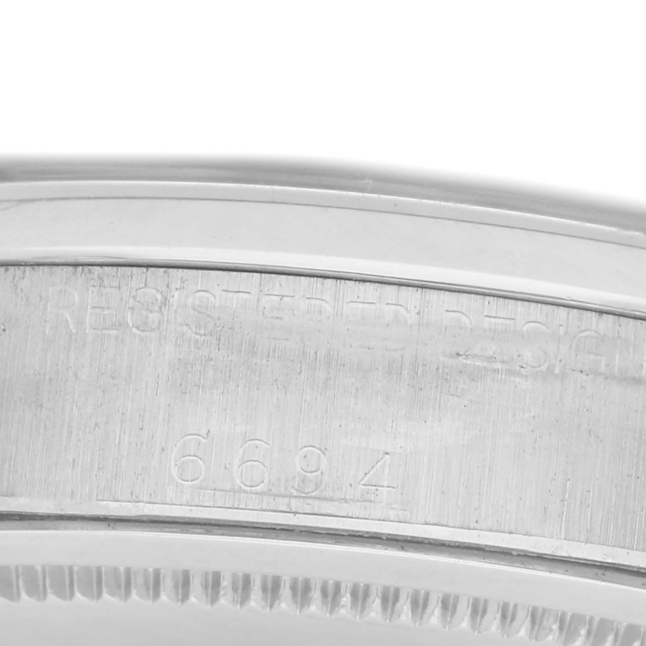 The image shows a close-up of the side of a Rolex Date 6694 Men's Stainless Steel Black Dial watch case with engraved details and a fluted bezel.