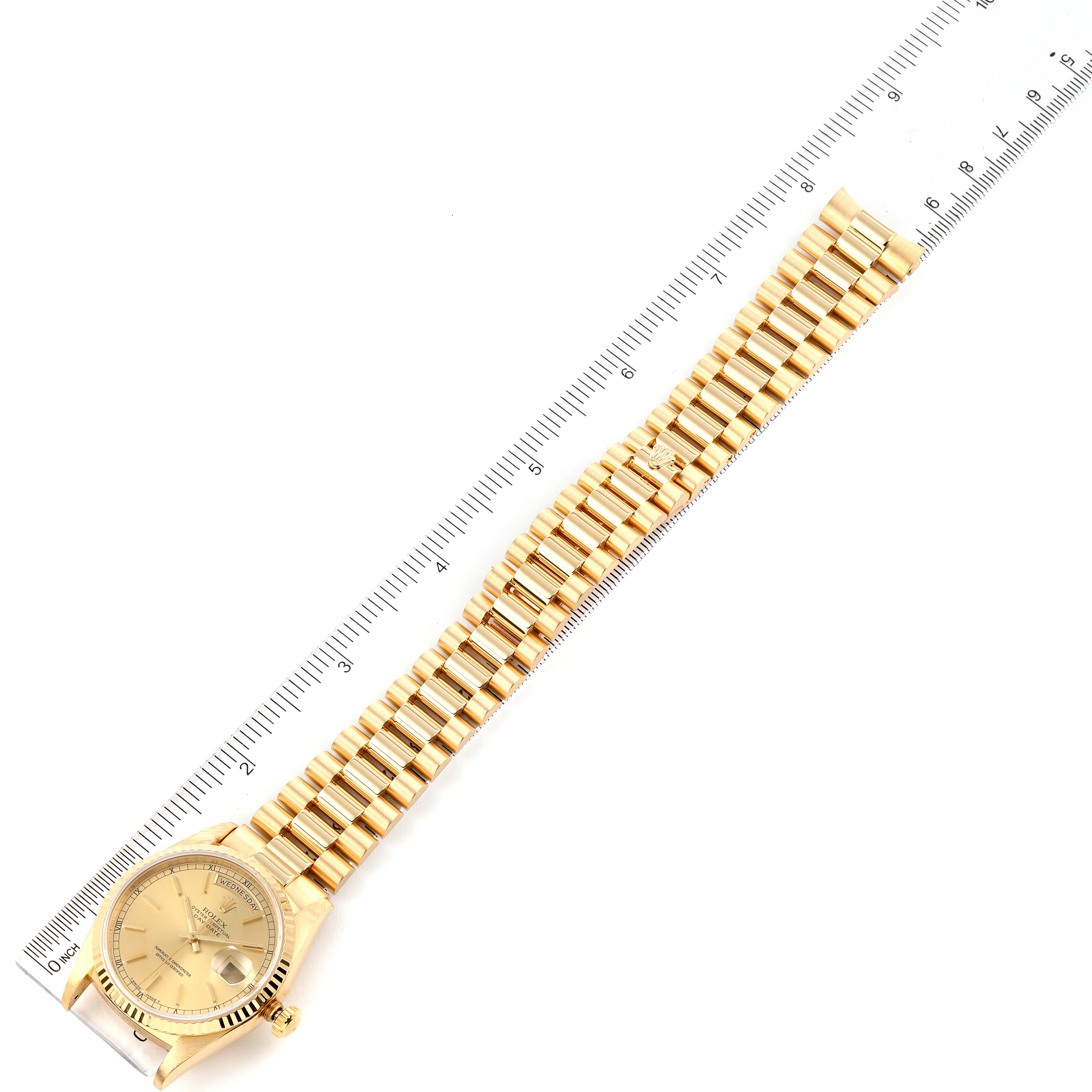 The image shows a top view of a gold Rolex President 18238 Men
s Yellow Gold Champagne Dial 18238 Men
s Yellow Gold Champagne Dial model watch placed next to a ruler.