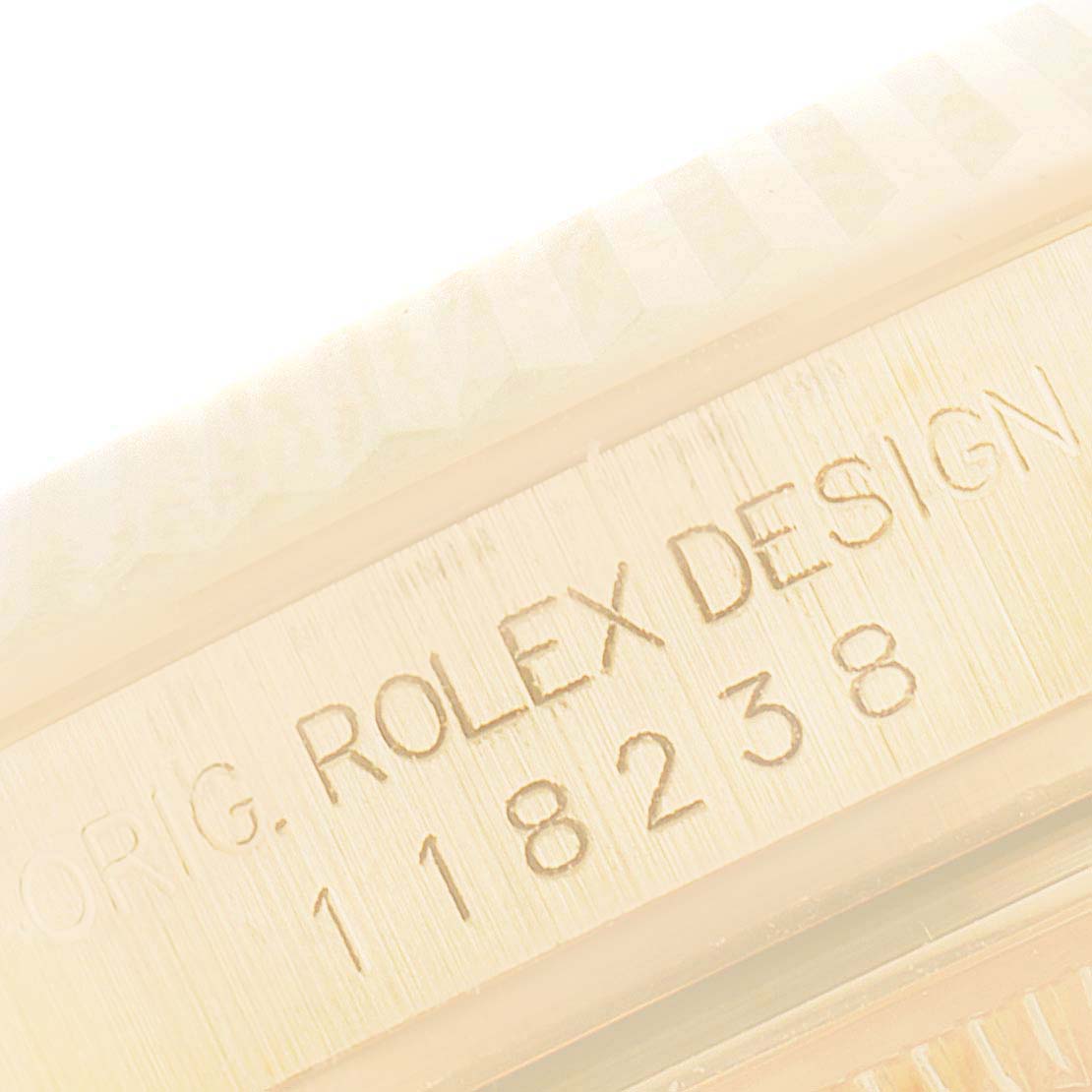 This close-up image of a Rolex President 118238 Men's Yellow Gold Mother of Pearl Dial 118238 Men's Yellow Gold Mother of Pearl Dial model shows the side of the watch case with "ROLEX DESIGN 118238" engraved on it.
