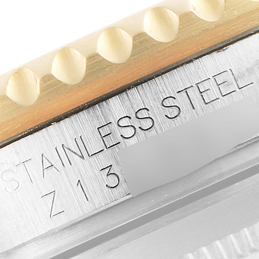 This close-up image of a Rolex Submariner 16613 Men's Steel and Gold (two tone) Black Dial 16613 Men's Steel and Gold (two tone) Black Dial watch shows the engraved text "STAINLESS STEEL" and part of the bezel with markers.