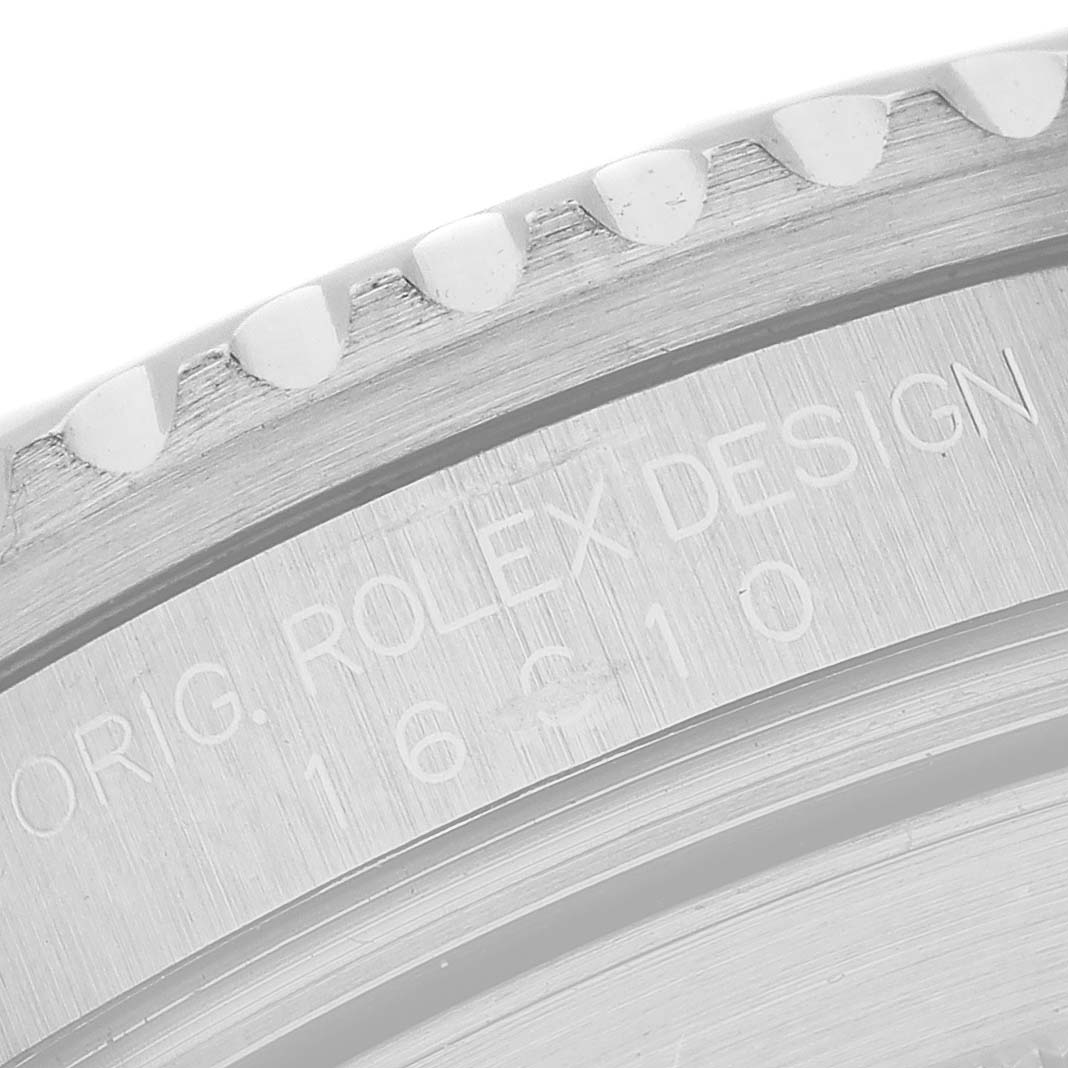 The image shows a close-up of the engraved edge of a Rolex Submariner 16610 Men's Stainless Steel Black Dial's case, highlighting its design details.