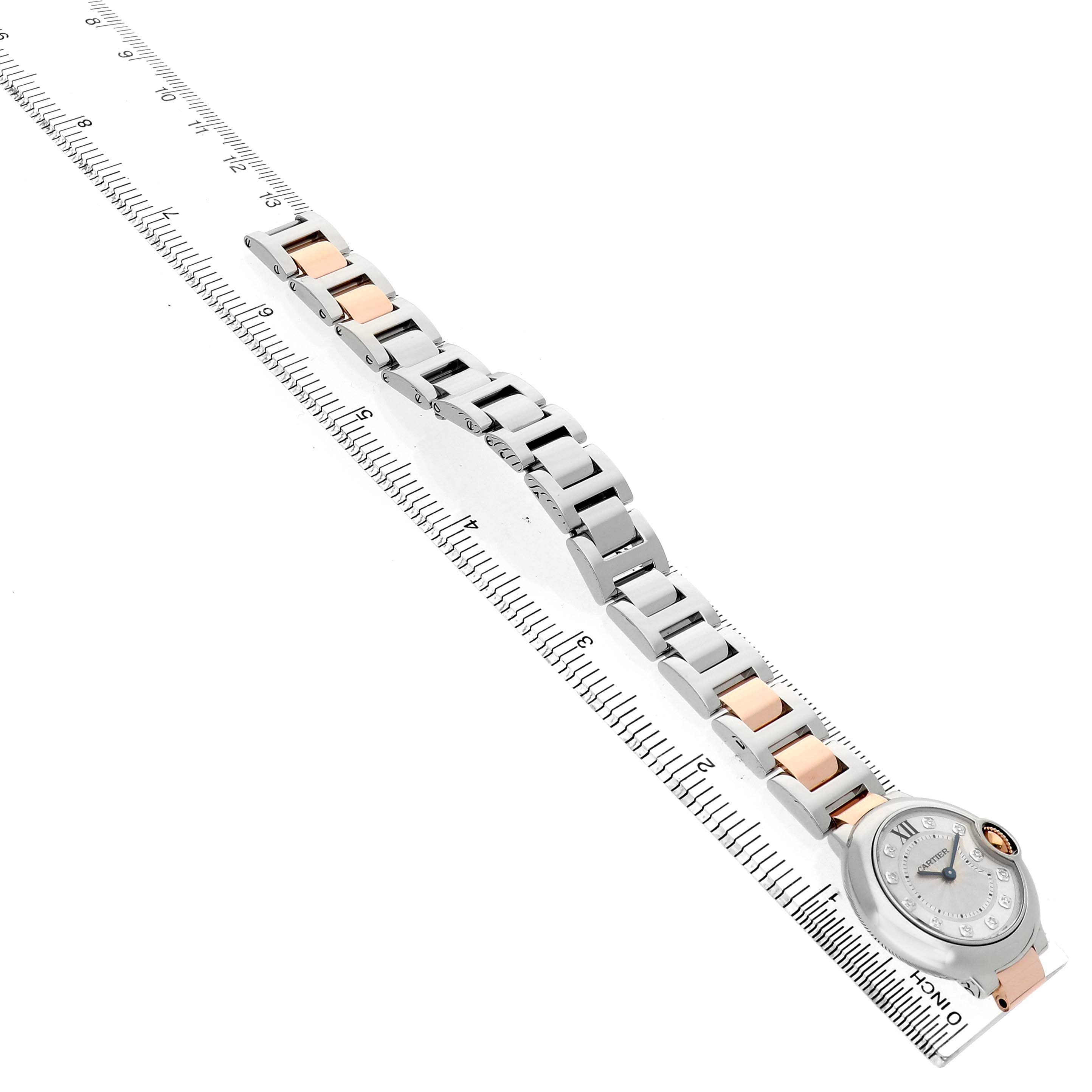 The Cartier Ballon Bleu WE902030 Women's Steel and Gold (two tone) Silver Dial watch is shown diagonally with its bracelet extended, highlighting the case and links alongside a ruler.