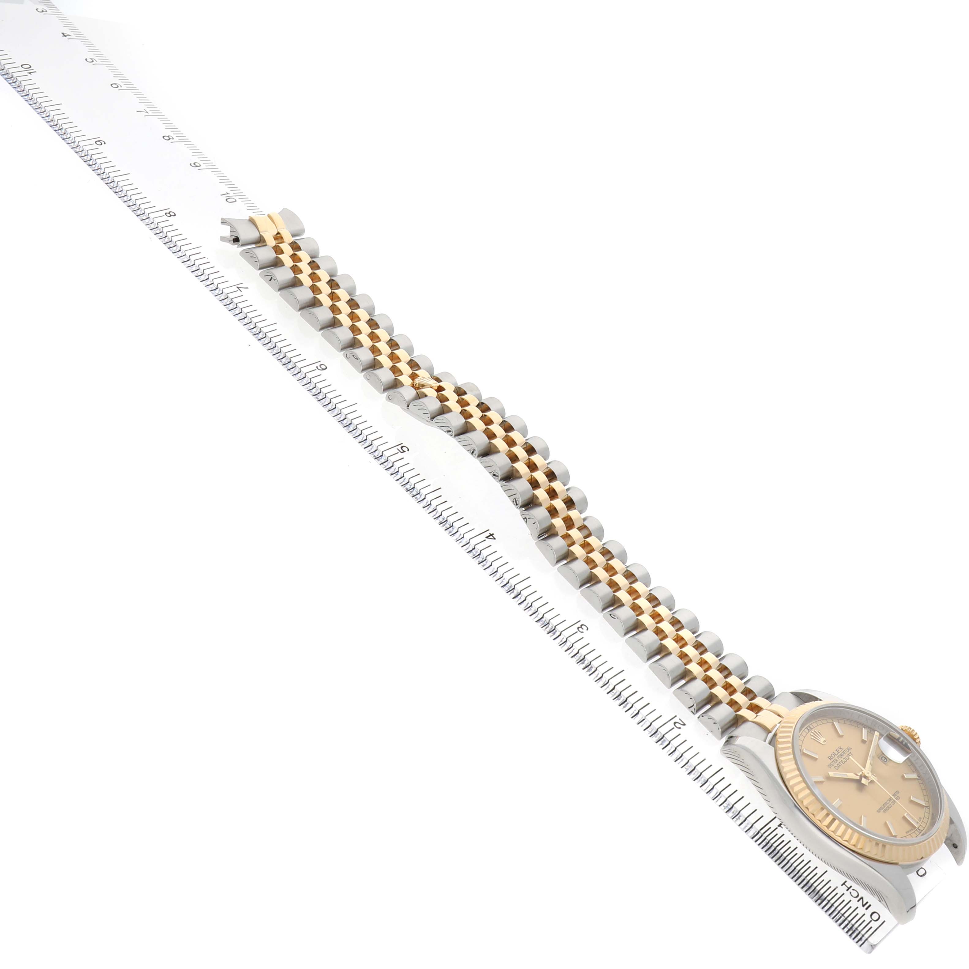 The Rolex Datejust 116233 Men's Steel and Gold (two tone) Champagne Dial watch is angled sideways, showing the face and the full length of the two-toned bracelet against a ruler.