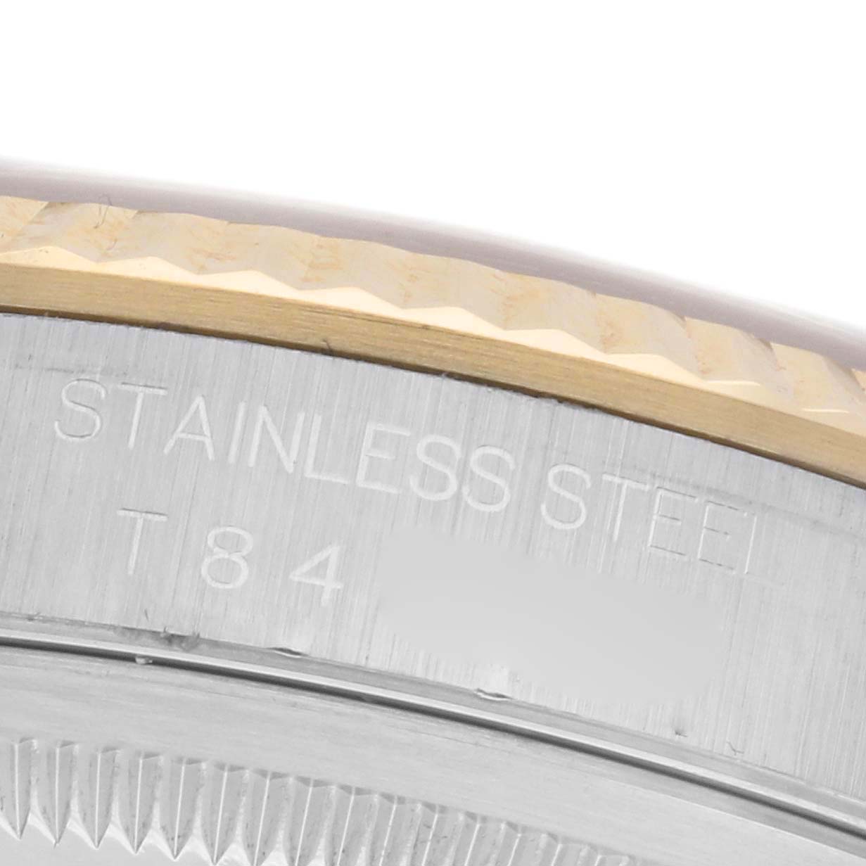 The image shows a close-up of the engraved side of a Rolex Datejust 16233 Men
s Steel and Gold (two tone) Champagne Dial 16233 Men
s Steel and Gold (two tone) Champagne Dial watch, highlighting "STAINLESS STEEL" text and a fluted bezel.