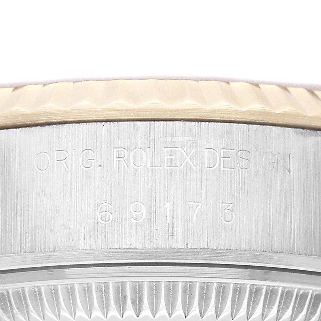 This image shows the side of a Rolex Datejust 69173 Women
s Steel and Gold (two tone) Champagne Dial 69173 Women
s Steel and Gold (two tone) Champagne Dial watch case with the engraved model number 69173 and the words "ORIG. ROLEX DESIGN."