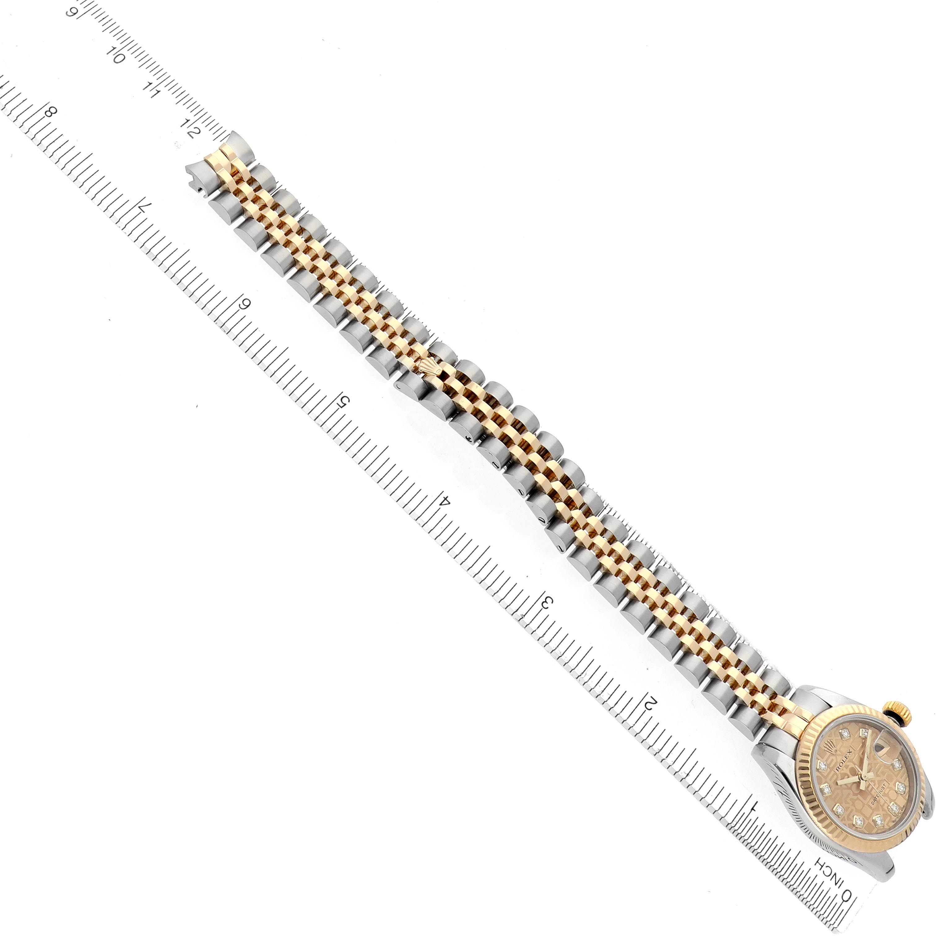 The Rolex Datejust 179173 Women's Steel and Gold (two tone) Champagne Dial 179173 Women's Steel and Gold (two tone) Champagne Dial watch is shown from an overhead angle, with its gold and silver bracelet fully extended alongside a ruler.