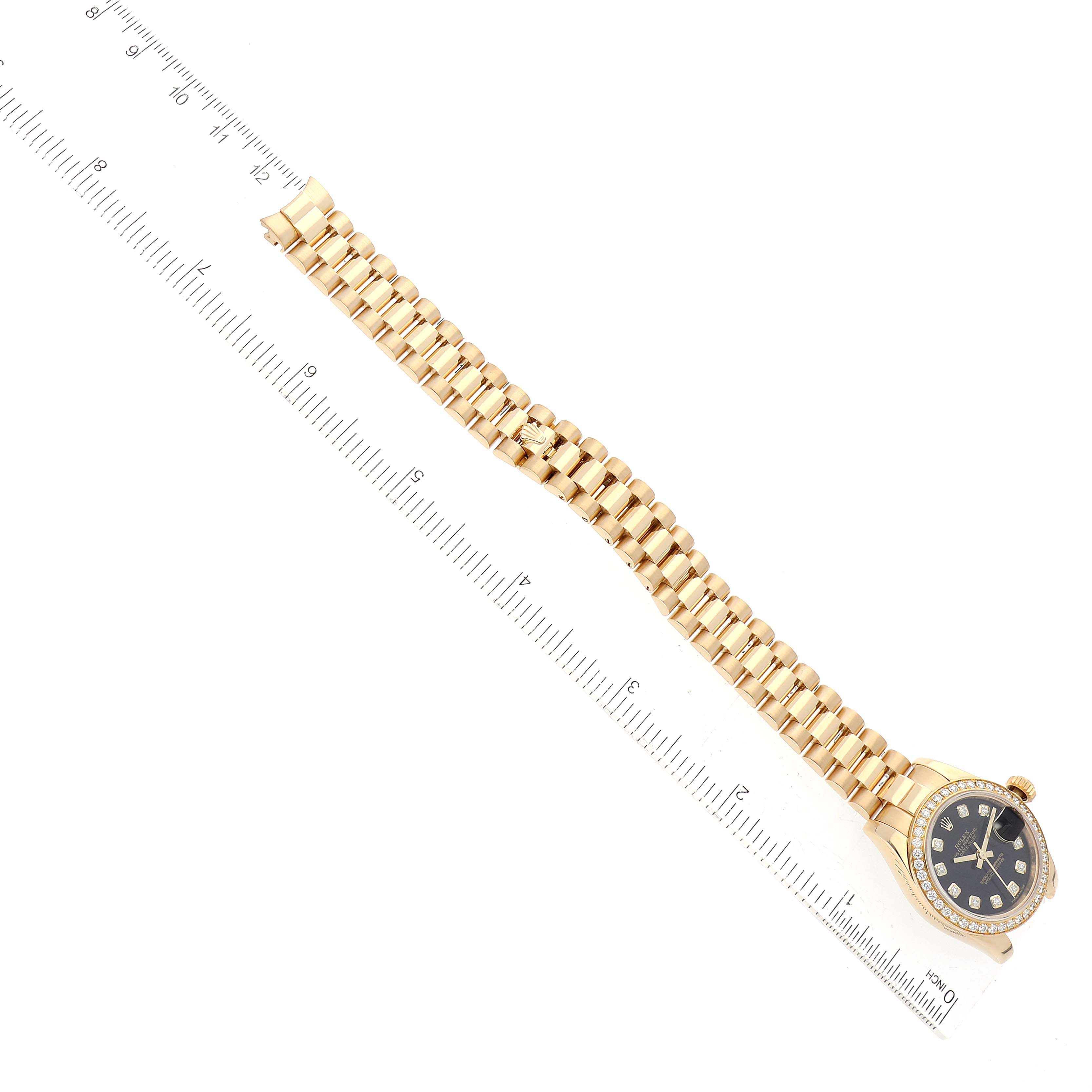 The image shows a Rolex President 179138 Women's Yellow Gold Black Dial 179138 Women's Yellow Gold Black Dial model watch laid flat, including the face, band, and clasp, next to a ruler for scale.