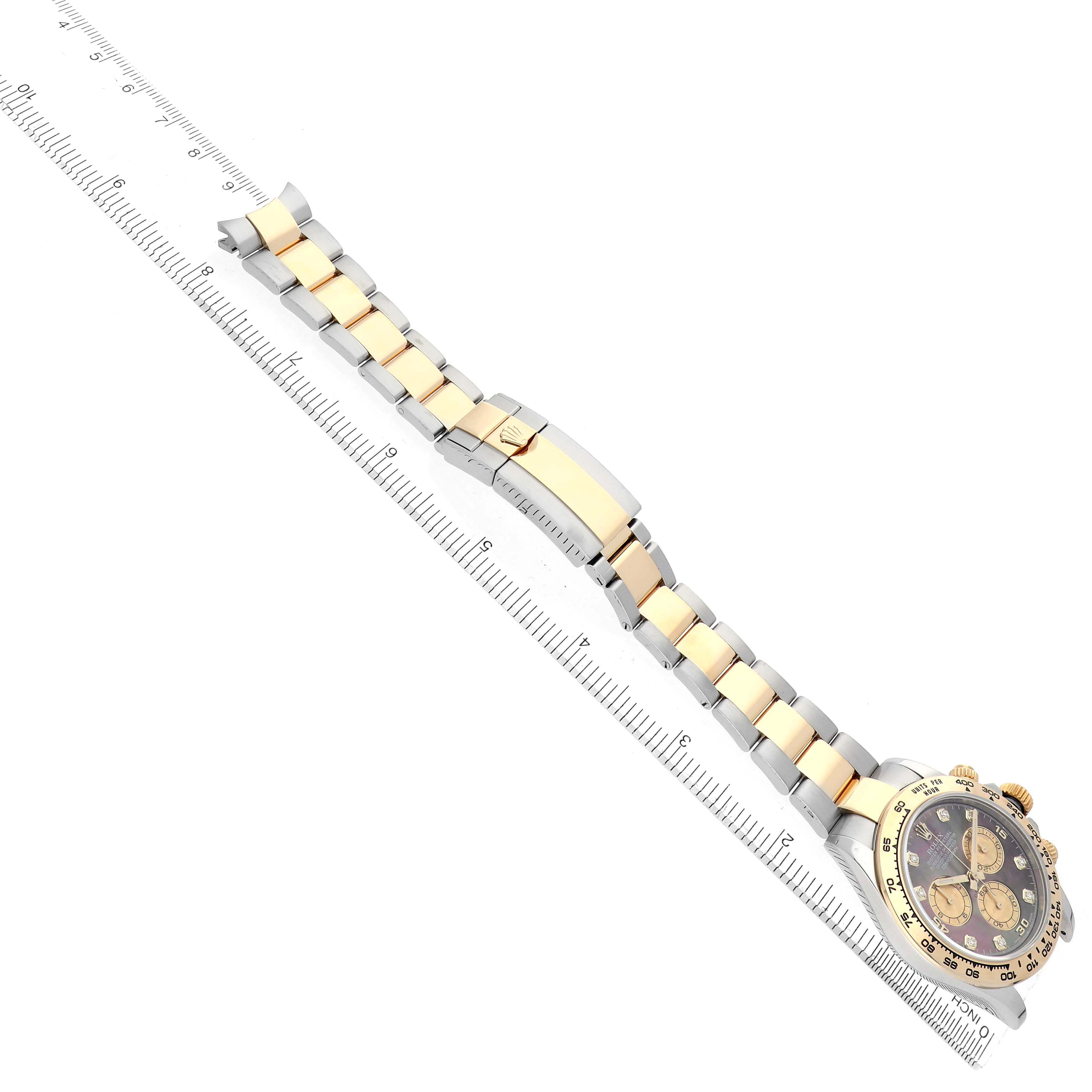 The Rolex Daytona 116503 Men's Steel and Gold (two tone) Mother of Pearl Dial watch is displayed from an angled side view, showing the full bracelet and clasp alongside a ruler for scale.