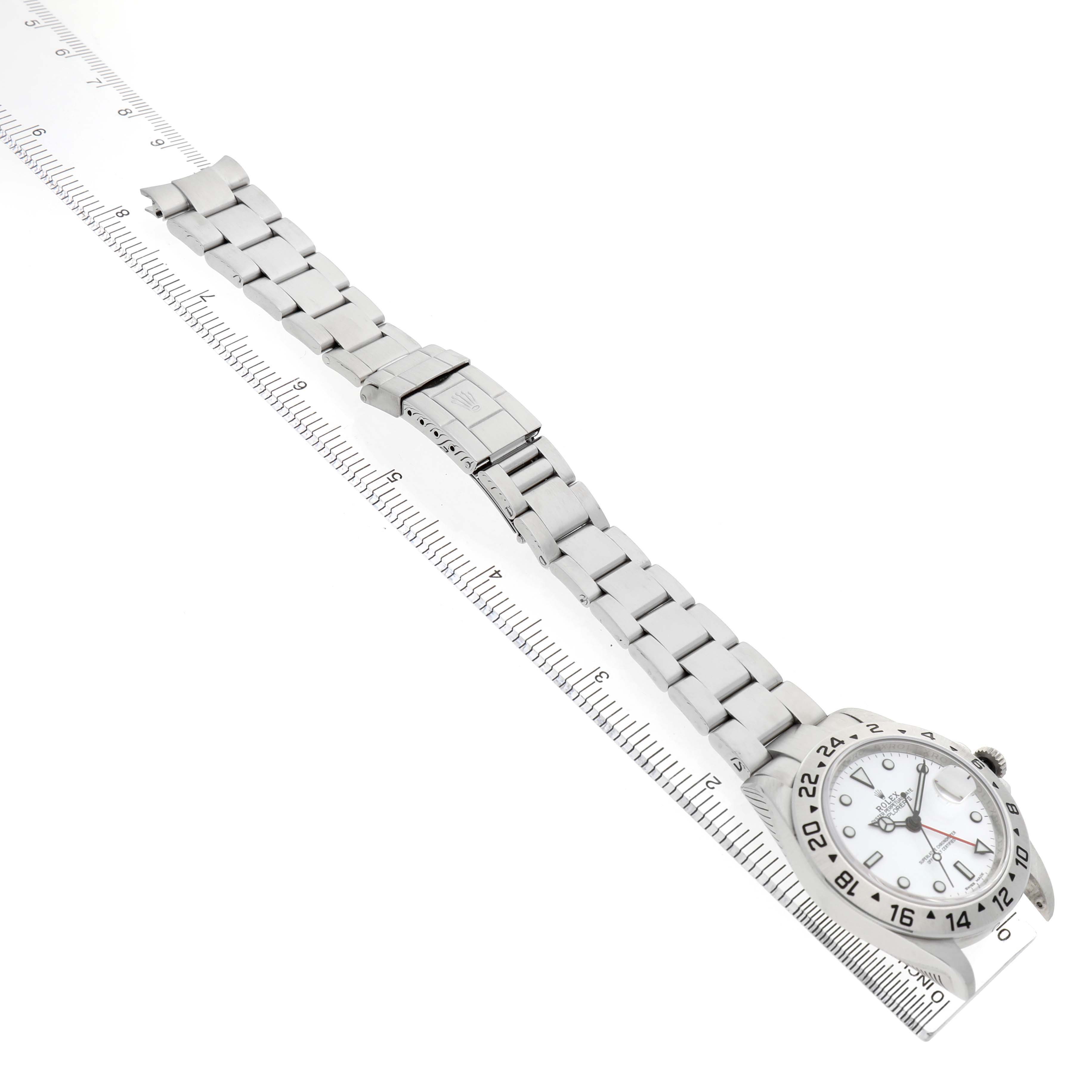 The Rolex Explorer 16570 T Men's Stainless Steel White Dial watch is shown laid flat with a side view of the bracelet and clasp, alongside a ruler for scale.