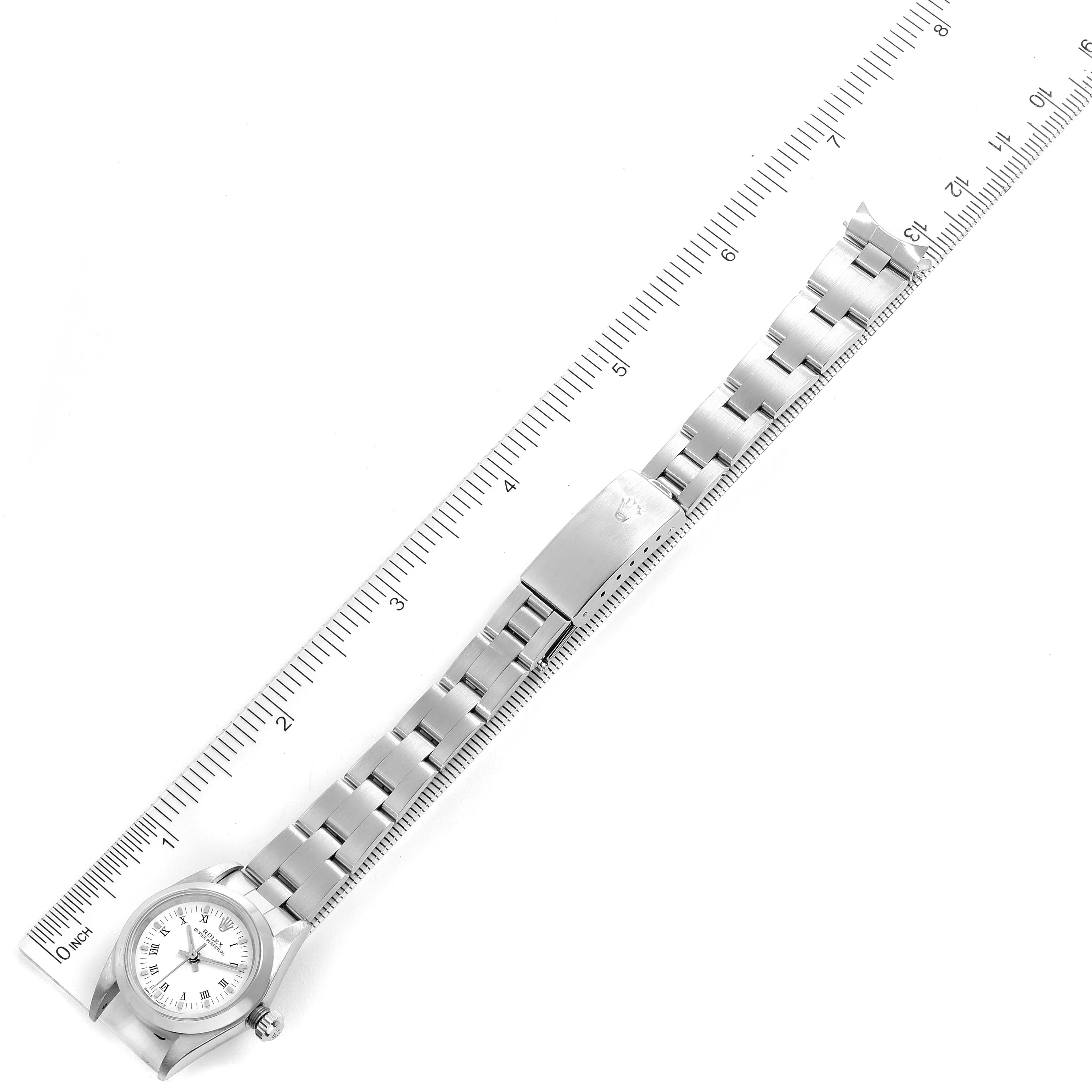 The image shows a top view of a Rolex Oyster Perpetual 76080 Women's Stainless Steel White Dial 76080 Women's Stainless Steel White Dial watch, highlighting the dial, bracelet, and clasp, with a ruler for scale.