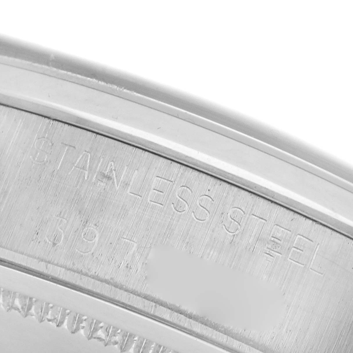 The image shows a close-up of the stainless steel part of a Rolex Date model's watch case, focusing on inscribed details.