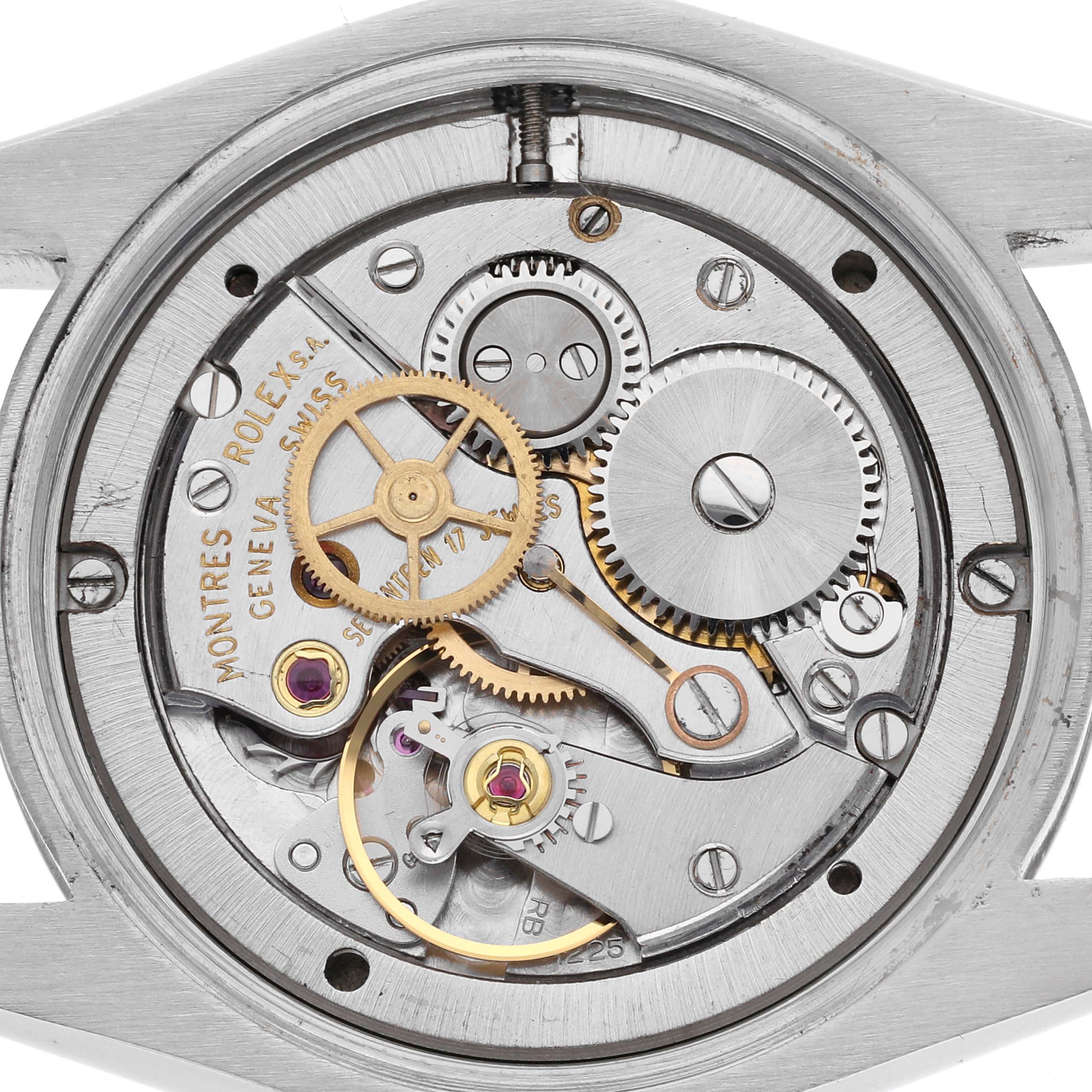 The image shows the internal mechanism of a Rolex Date model, highlighting gears and cogs from a top view angle.