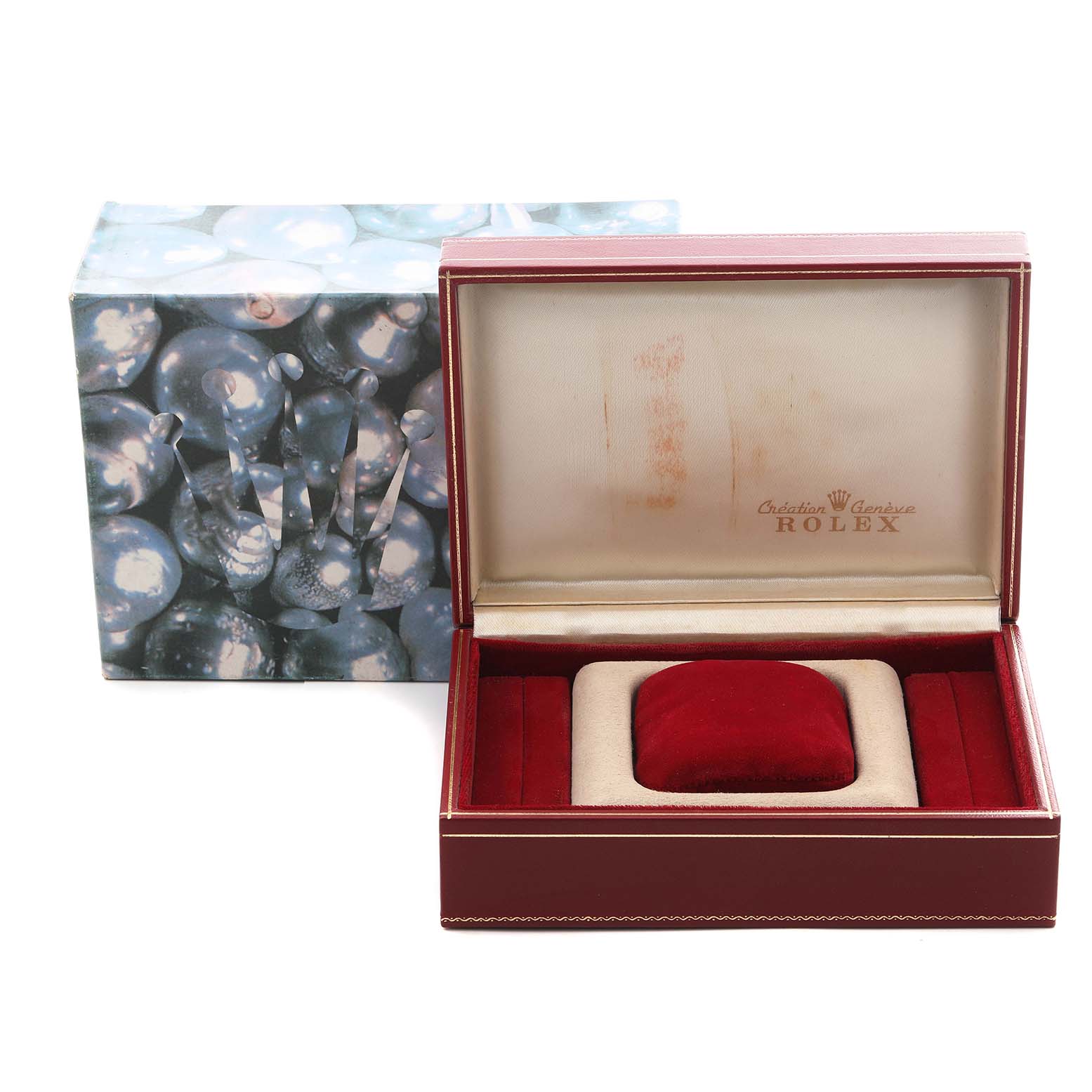 The image shows an open Rolex watch box with a velvet interior, alongside its outer box featuring a decorative design.