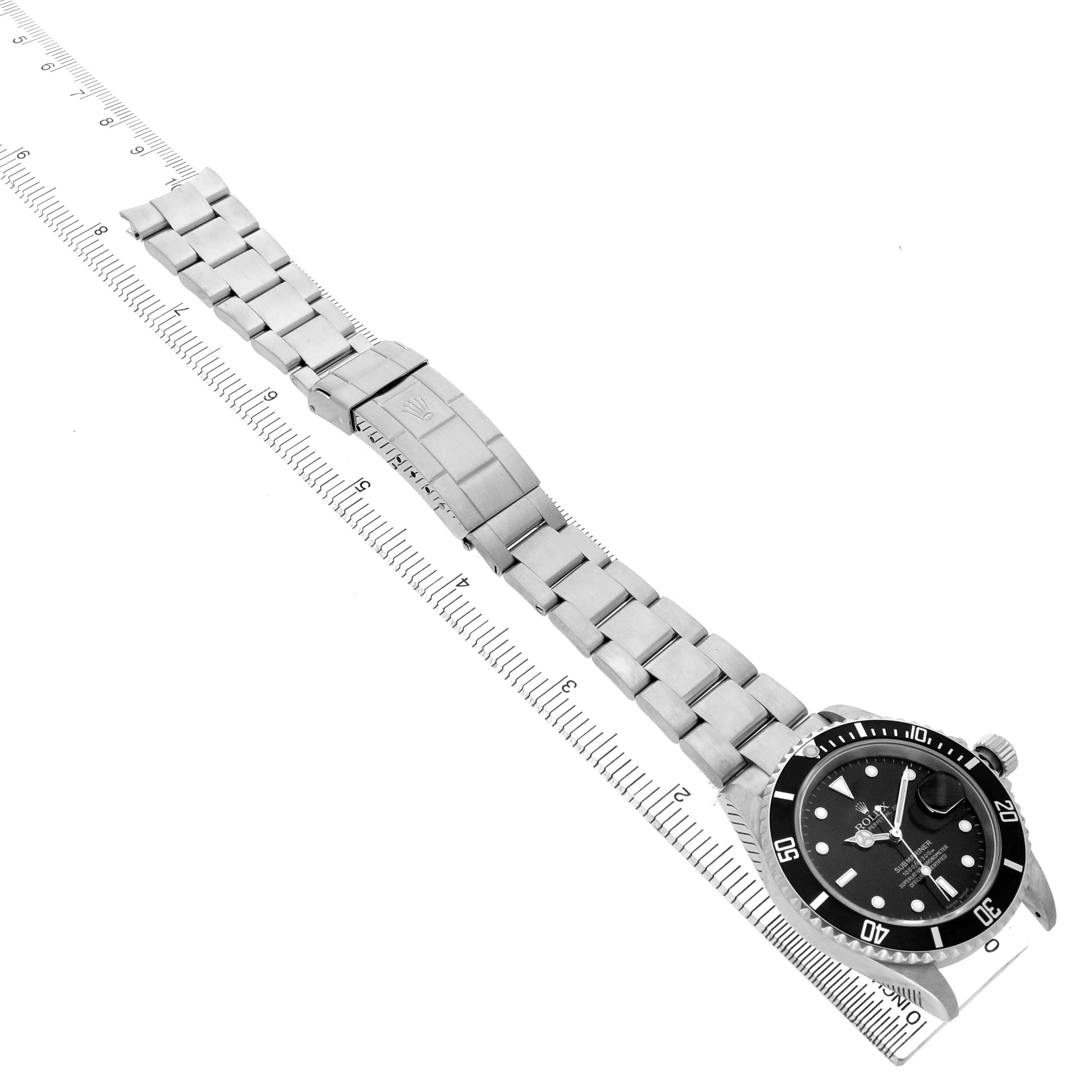 The Rolex Submariner 16610 T Men's Stainless Steel Black Dial watch is shown from a top-down angle, highlighting the watch face, bezel, and stainless steel bracelet alongside a ruler.