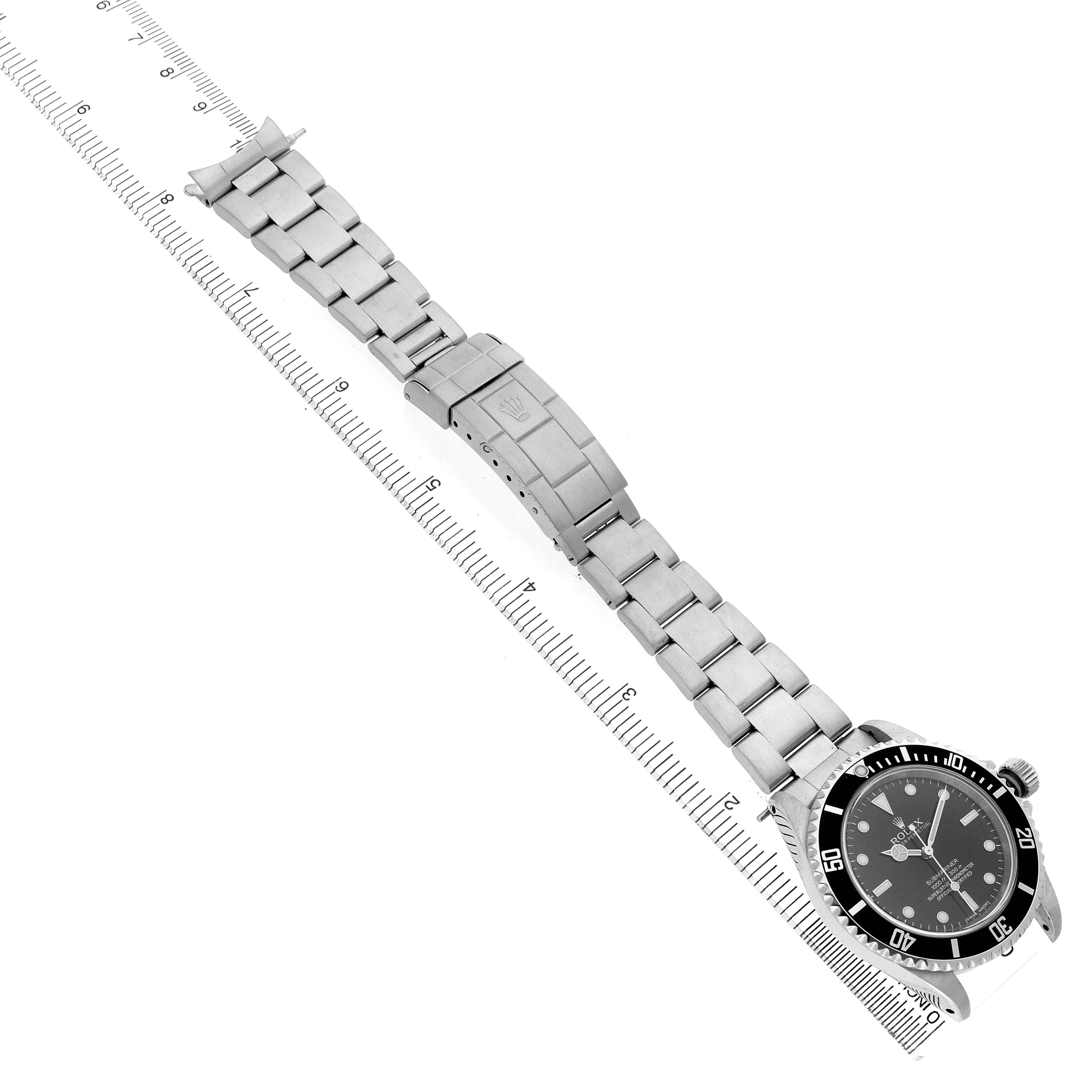 The Rolex Submariner 14060M Men's Stainless Steel Black Dial watch is shown from a top-down angle with the bracelet extended along a ruler.