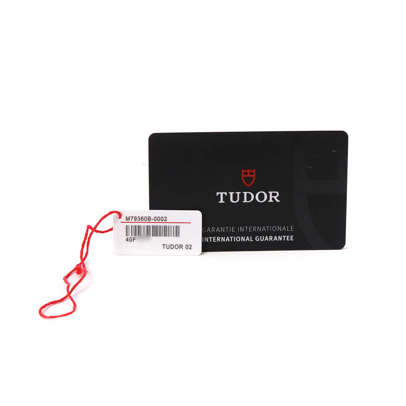 The image shows a Tudor Heritage Chrono M79360B-0002 Men's Stainless Steel Blue Dial warranty card and a tag with a red string.