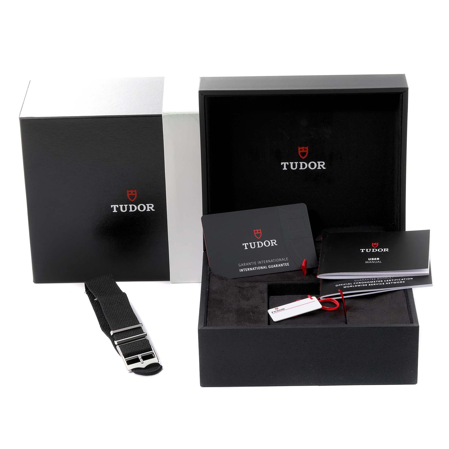 The image shows the packaging, warranty card, manual, and a strap for the Tudor Heritage Black Bay 79230G Men's Stainless Steel Black Dial 79230G Men's Stainless Steel Black Dial watch.